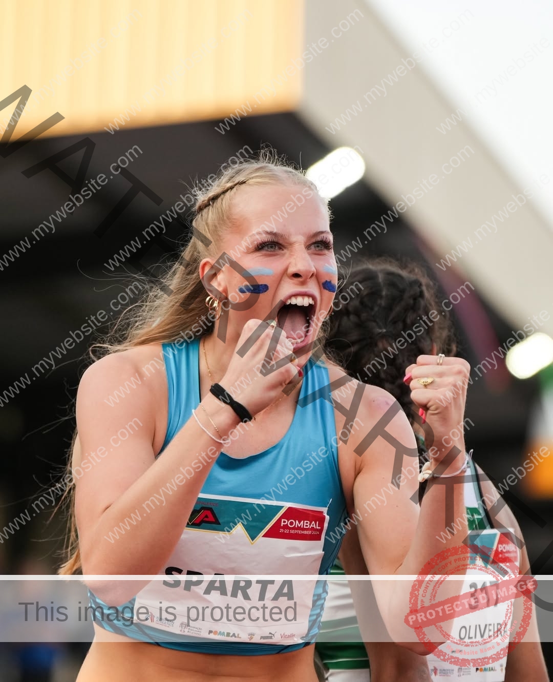 amaya-kruse-jorgensen-denmark-amayajorgensen-0257 Amaya Kruse Jorgensen, track and field star from Denmark, clenches her fists and shouts in a blue SPARTA top with face paint.