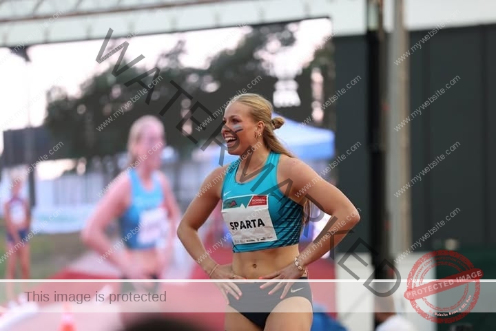 amaya-kruse-jorgensen-denmark-amayajorgensen-0267 Amaya Kruse Jorgensen, track and field star from Denmark, stands smiling outdoors in turquoise sports top, race bib SPARTA showing.