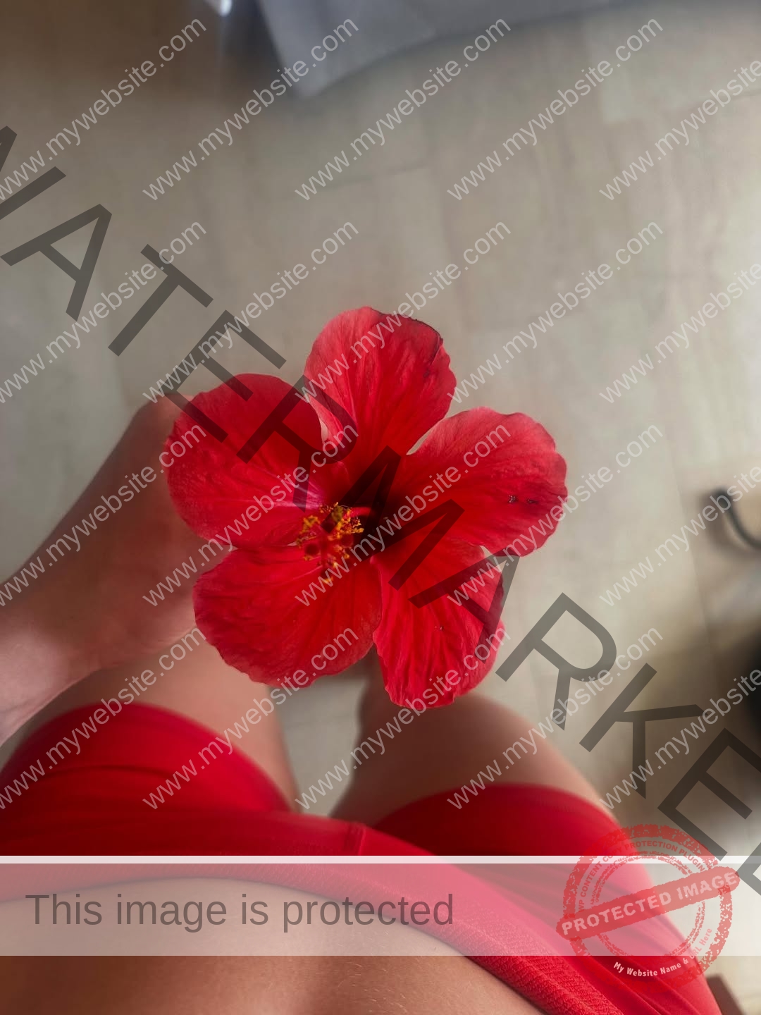 amaya-kruse-jorgensen-denmark-amayajorgensen-0289 Amaya Kruse Jorgensen, track and field star from Denmark, wears red shorts and holds a red hibiscus flower, seen from above.