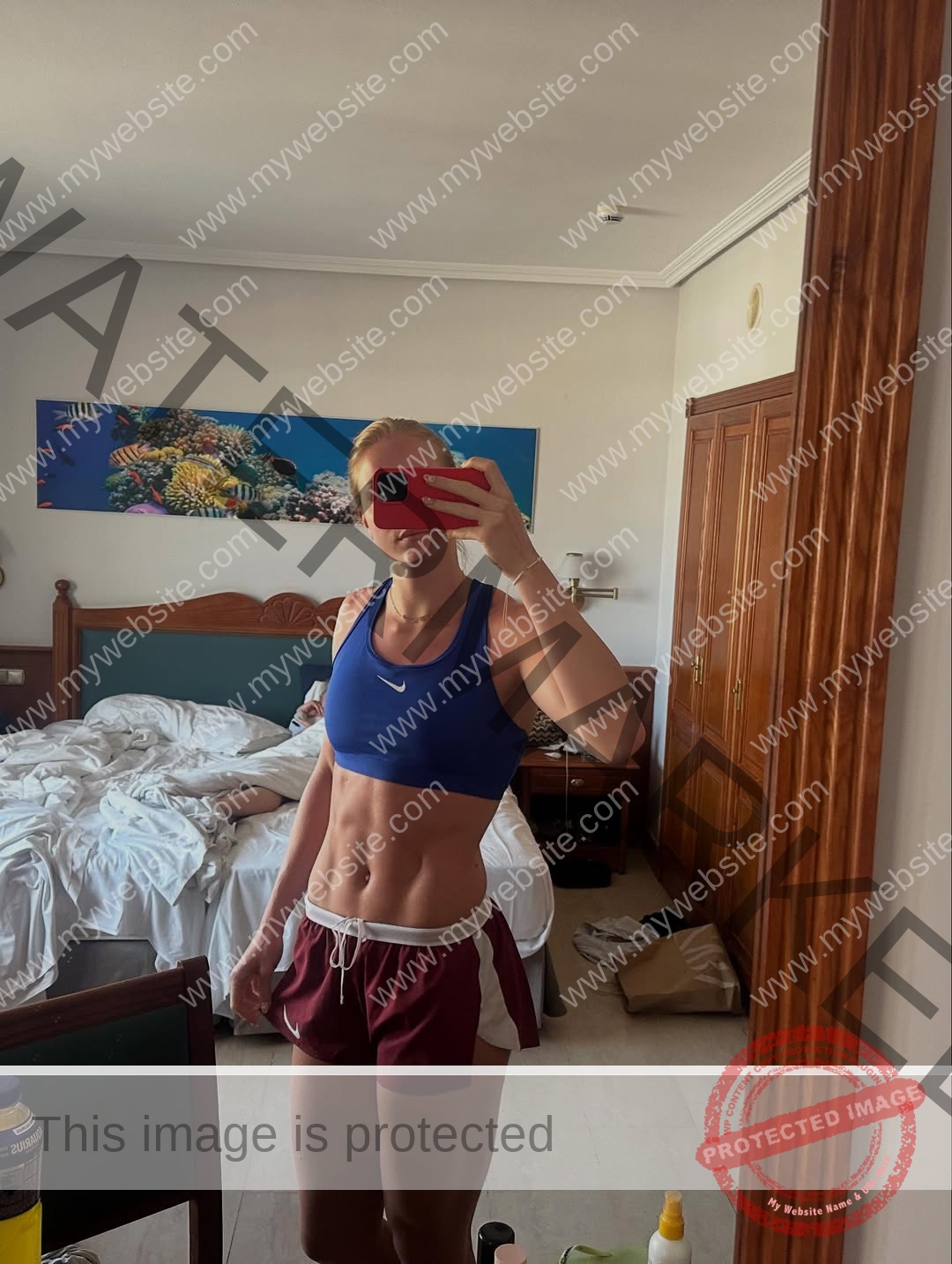 amaya-kruse-jorgensen-denmark-amayajorgensen-0294 Amaya Kruse Jorgensen, track and field star from Denmark, takes a mirror selfie in sporty attire; another person lies on the unmade bed.