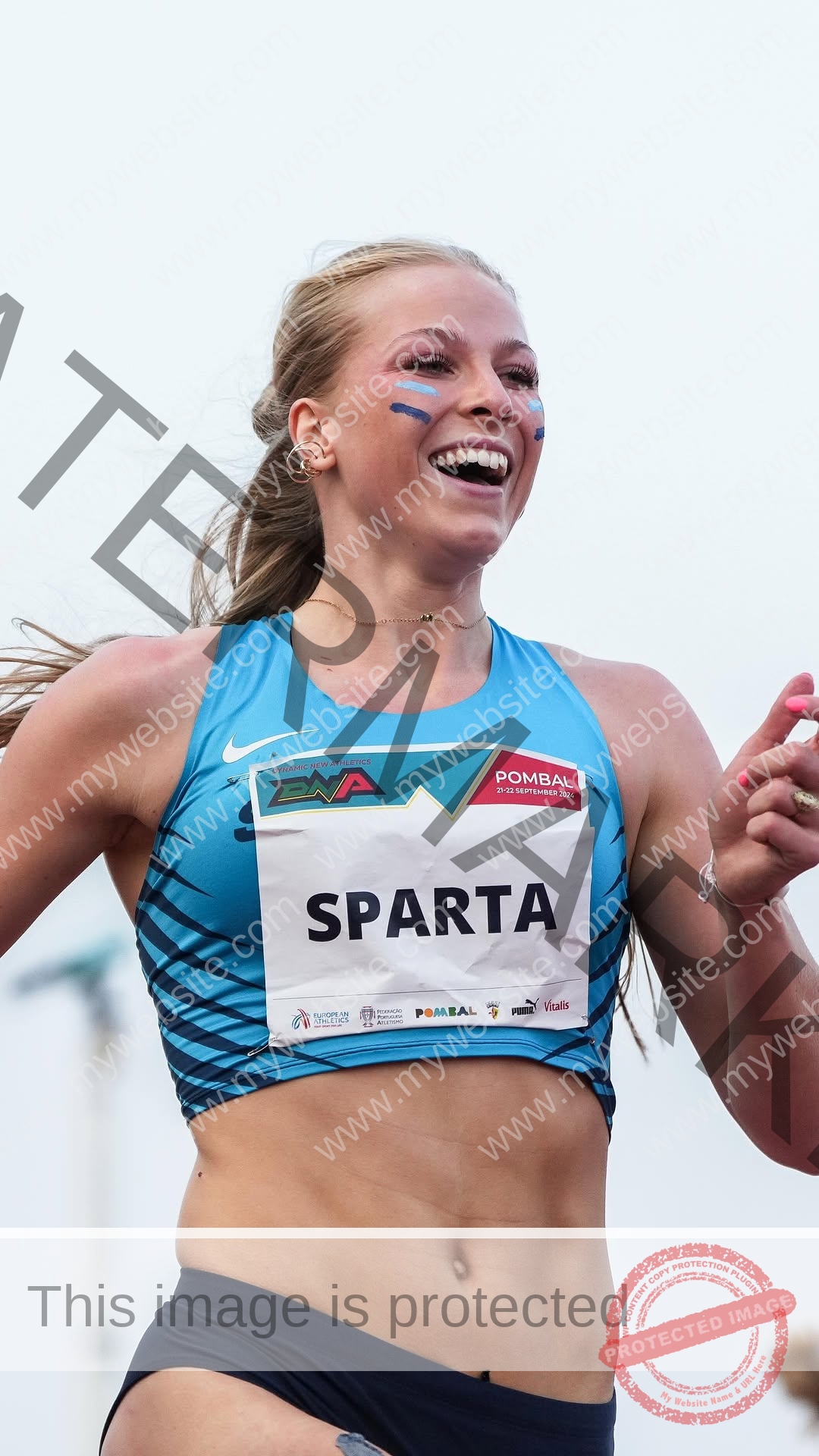 amaya-kruse-jorgensen-denmark-amayajorgensen-0310 Amaya Kruse Jorgensen, track and field star from Denmark, smiles with arms raised in blue gear, joyful after a race.