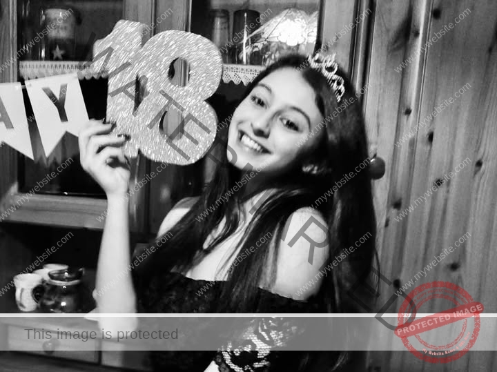 anabel-vitale-italy-anabelvitale-0398 Anabel Vitale, track and field star from Italy, wears a tiara, smiling and holding a glittery 18 sign by a cabinet with birthday decor.