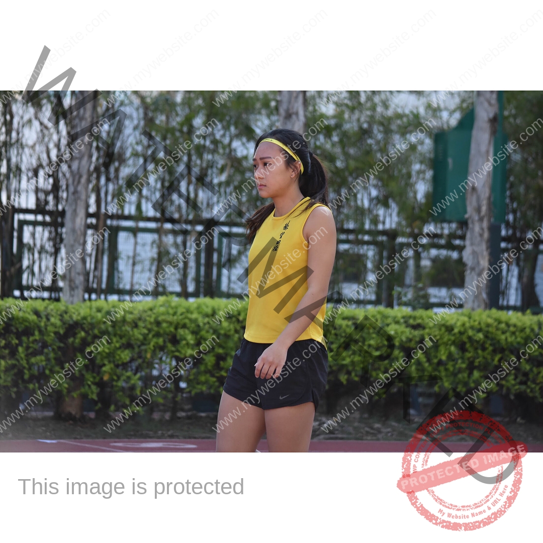 chan-pui-kei-hong-kong-chanpuikeii-02863 Chan Pui Kei, track and field star from Hong Kong, wears a yellow sleeveless top and black shorts walking on an outdoor track.