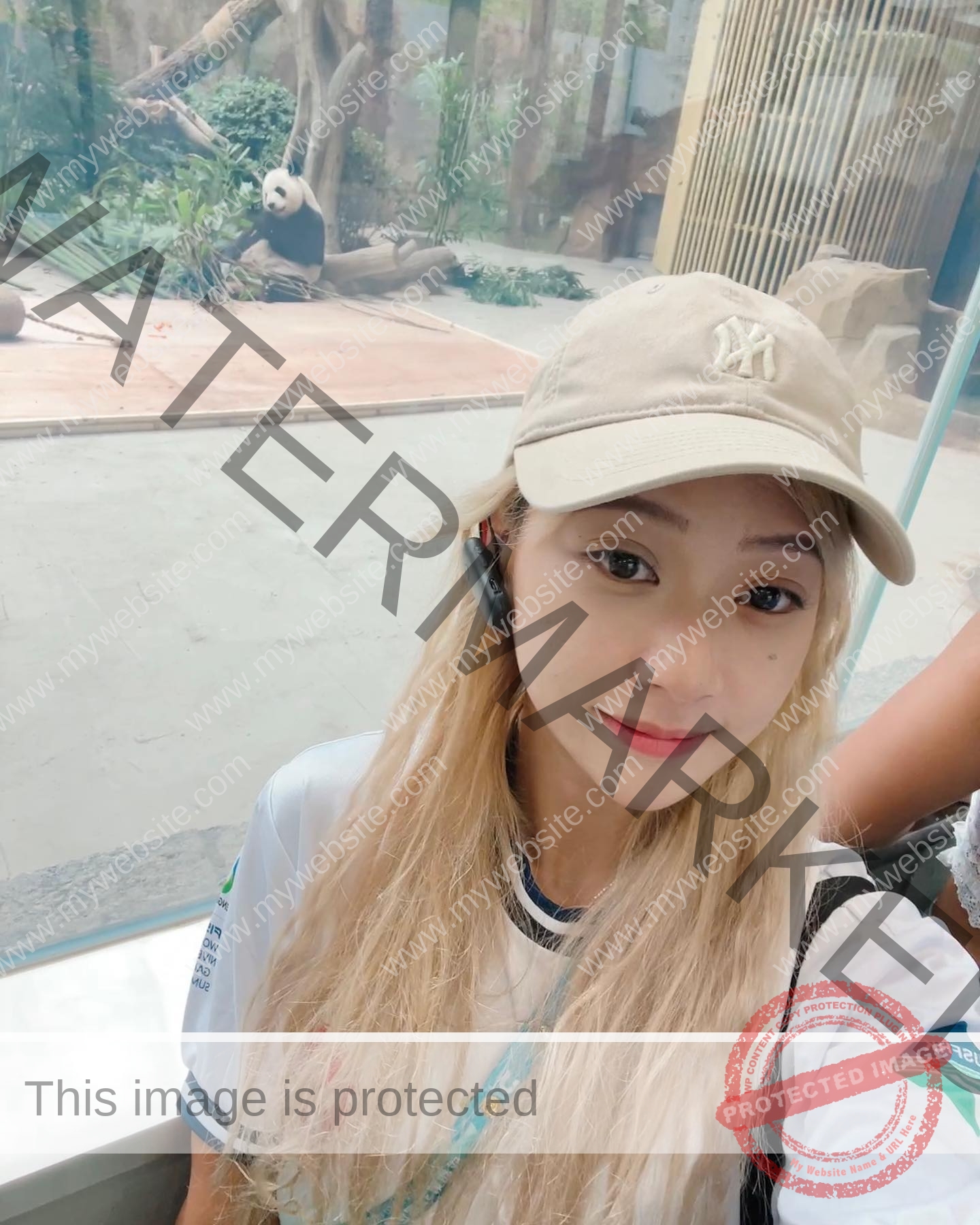 chan-pui-kei-hong-kong-chanpuikeii-02939 Chan Pui Kei, track and field star from Hong Kong, with long blonde hair and a beige cap, takes a selfie near a panda in greenery.