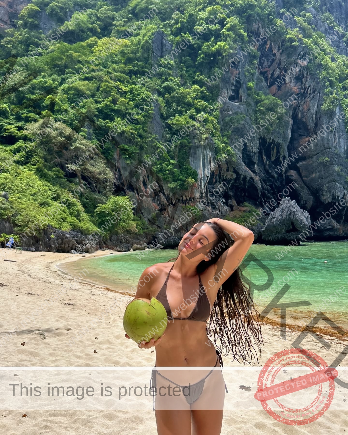 claudia-camacho-spain-clauudiacamacho-1457 Claudia Camacho, track and field star from Spain, in a brown bikini on a sandy beach, holding a green coconut and smiling.