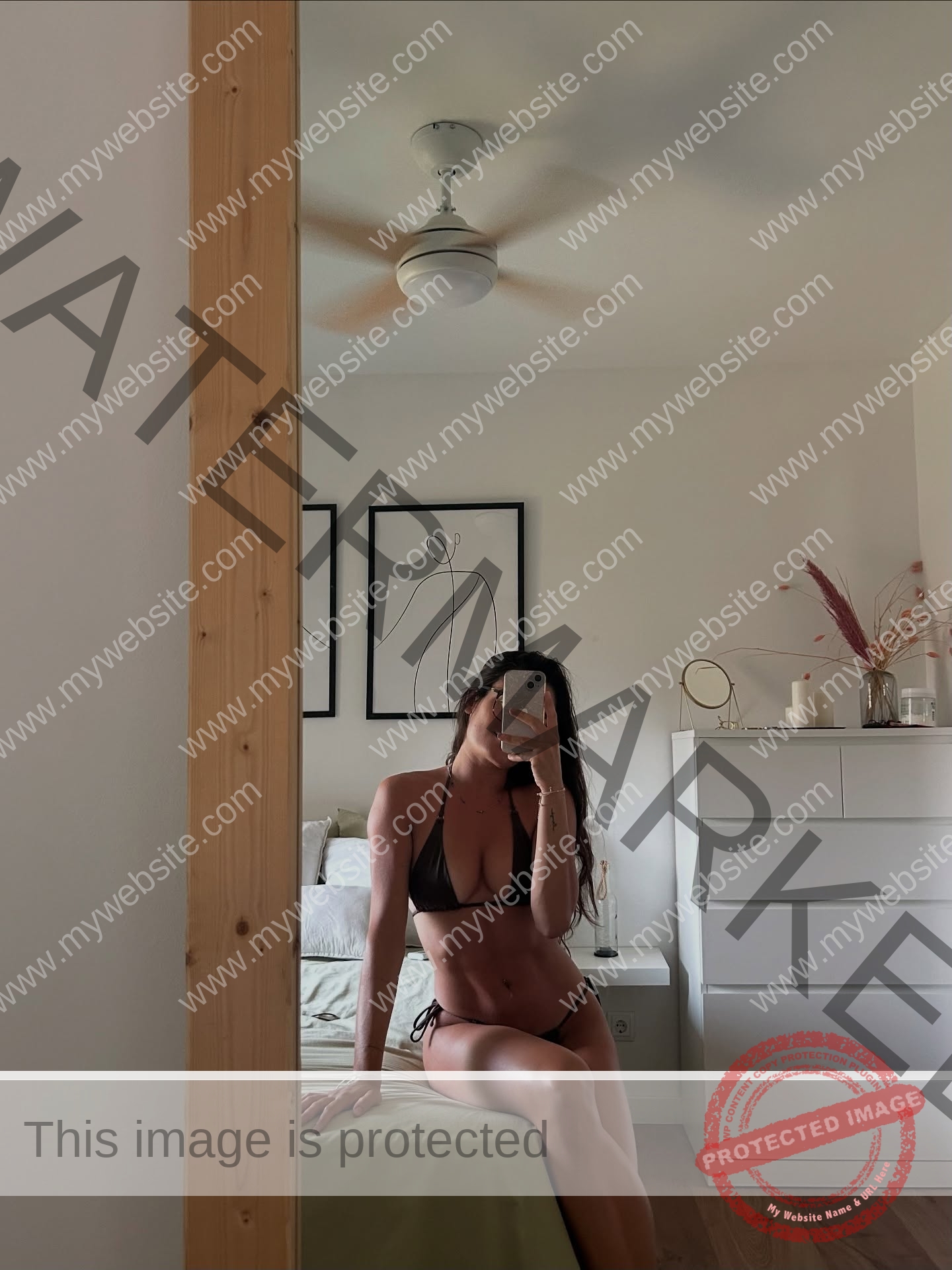 claudia-camacho-spain-clauudiacamacho-1471 Claudia Camacho, track and field star from Spain, in a black bikini takes a mirror selfie on a bed in a minimalistic bedroom.