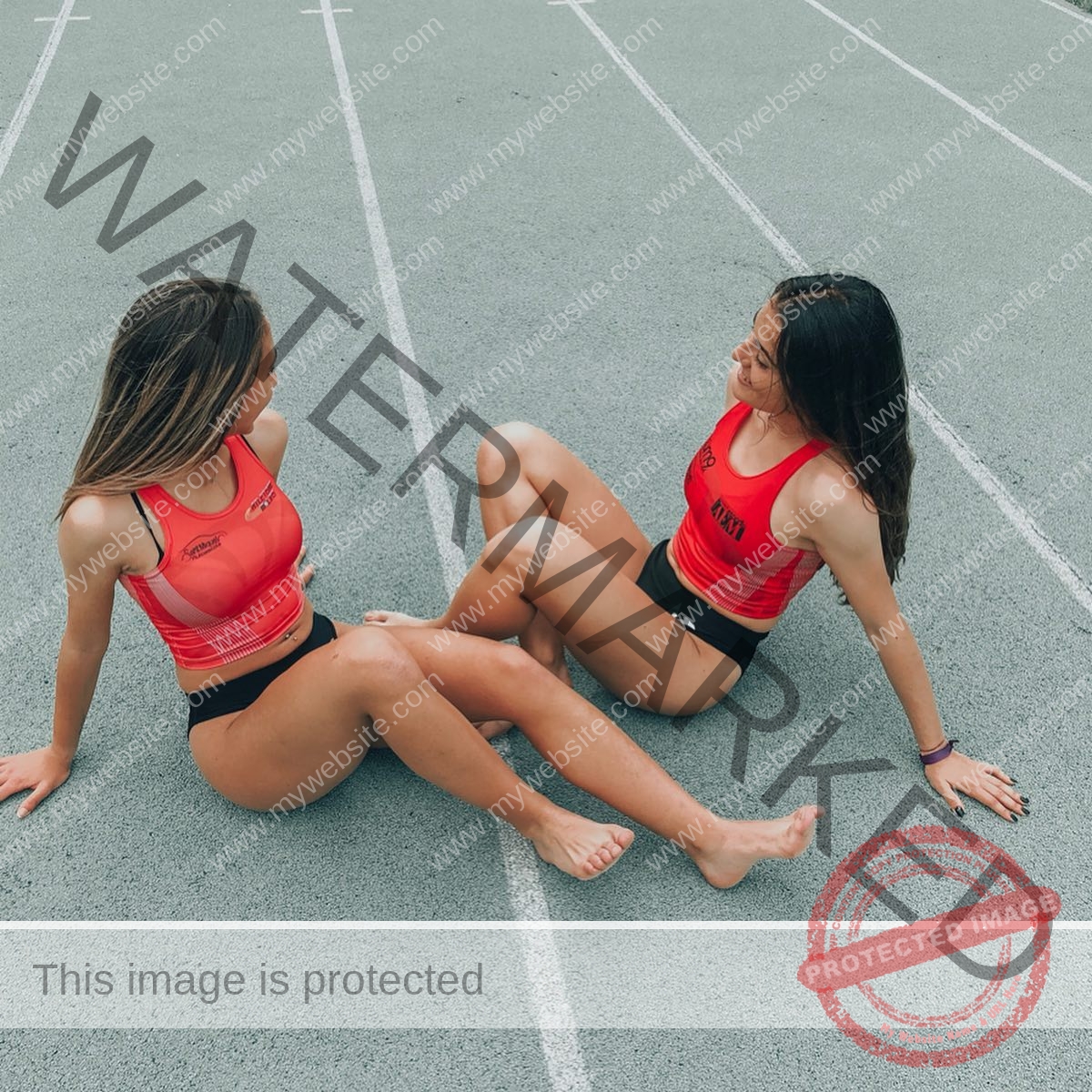 claudia-camacho-spain-clauudiacamacho-1498 Claudia Camacho, track and field star from Spain 'Two young women in red athletic outfits sit on a running track, relaxed and chatting.'.