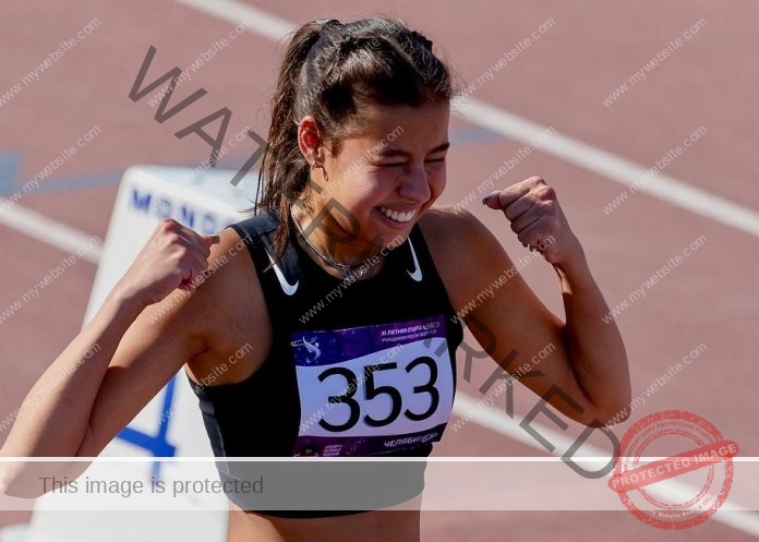 Elizaveta Golovataya, track and field star from Russia, wears a black sports top, bib 353, smiling and flexing on a track.