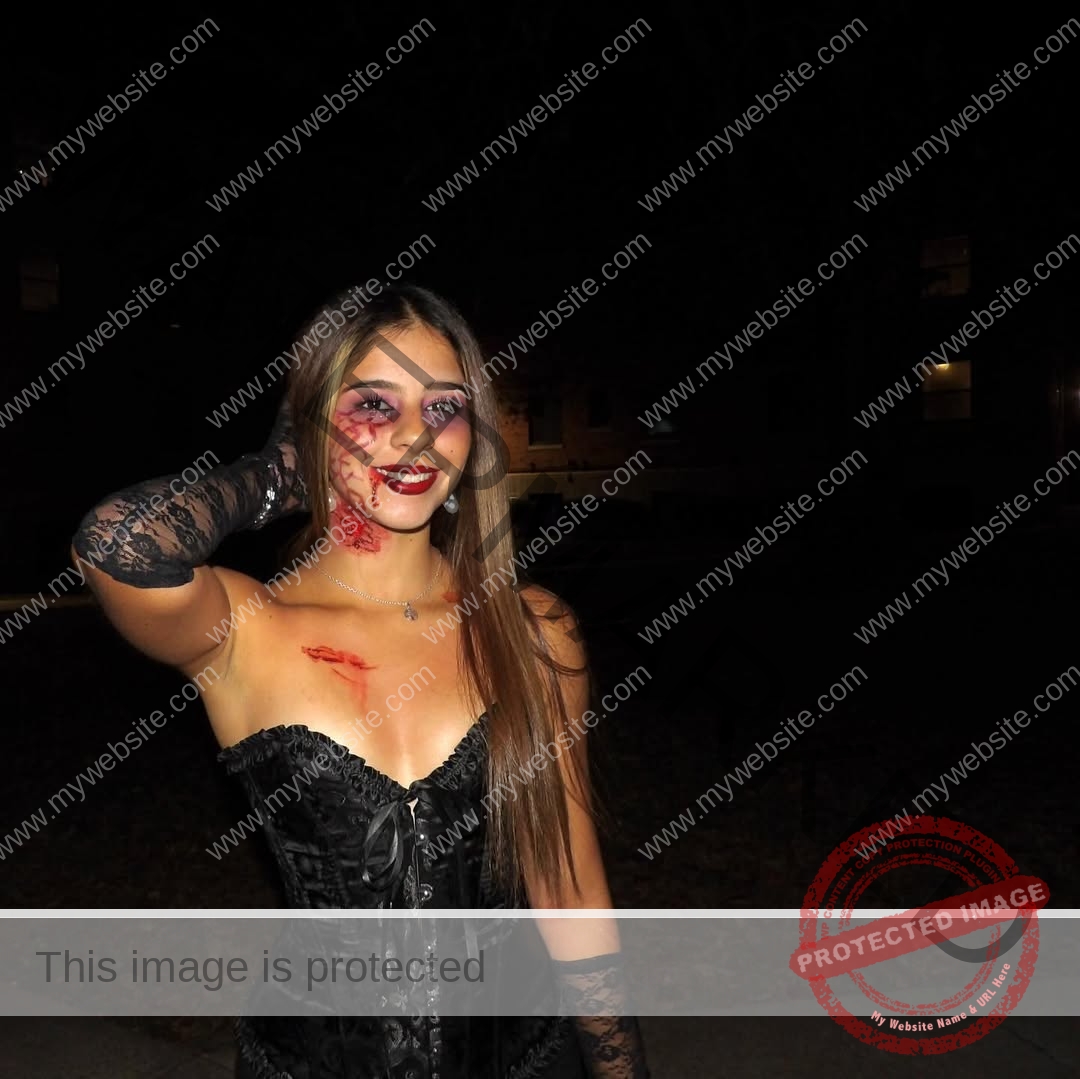 emma-deana-spain-emmadeana-15441 Emma Deana, track and field star from Spain, in a black corset dress at night, smiles with spooky fake blood makeup and poses.