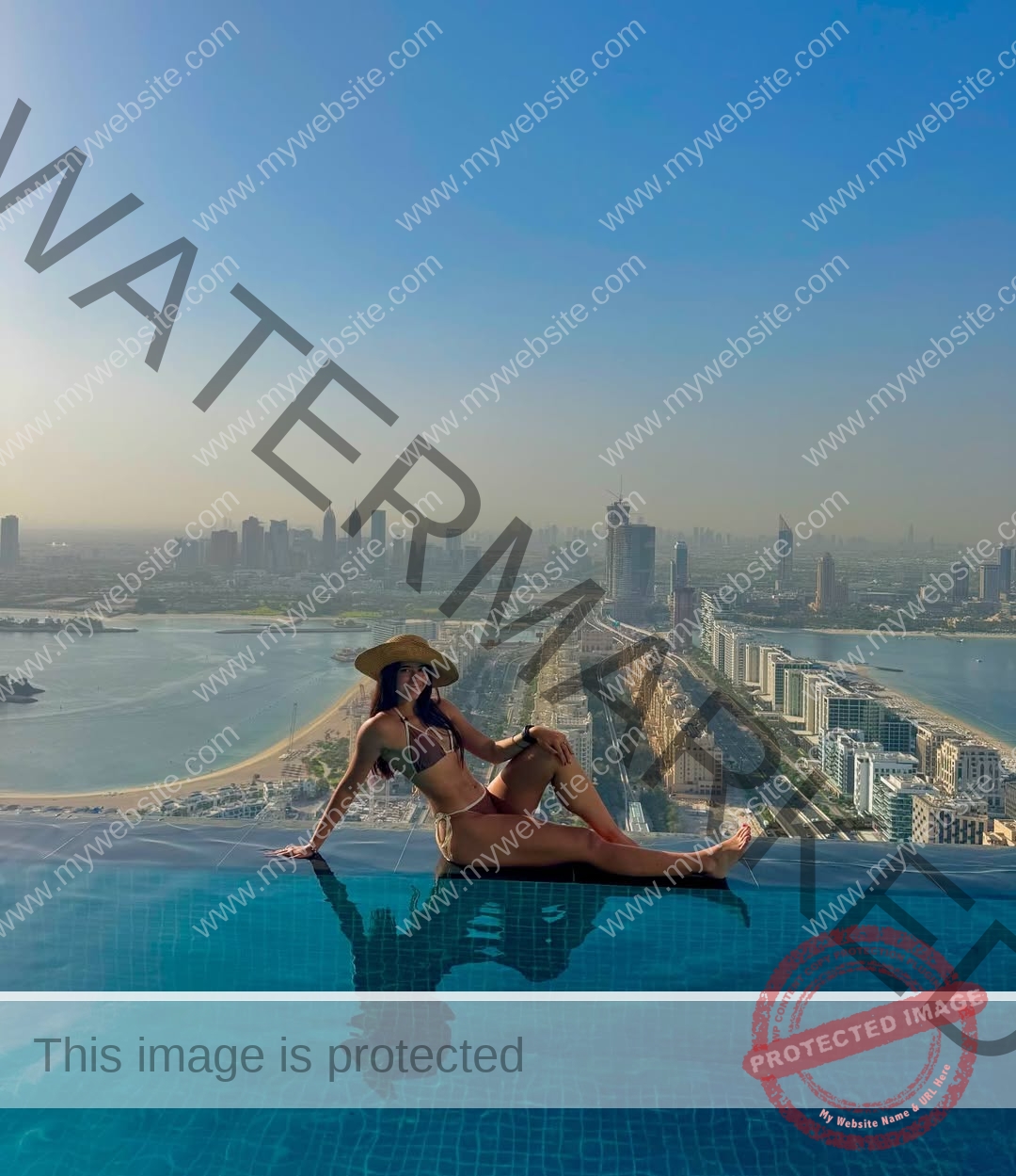 emma-deana-spain-emmadeana-15459 Emma Deana, track and field star from Spain, in a bikini and sunhat sits at an infinity pool edge, cityscape and water behind her.