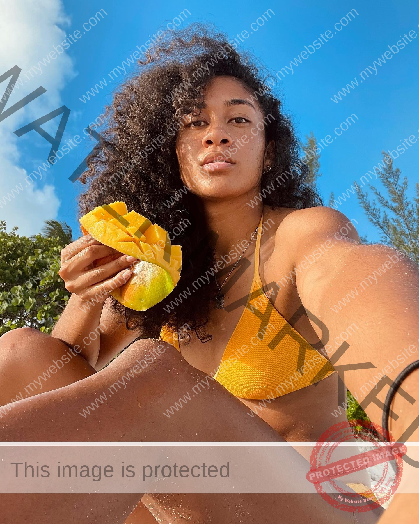 kristina-knott-philippines-knottyourcheese-x-18258 Kristina Knott, track and field star from Philippines, relaxes outdoors in a yellow bikini under blue skies, holding sliced mango.