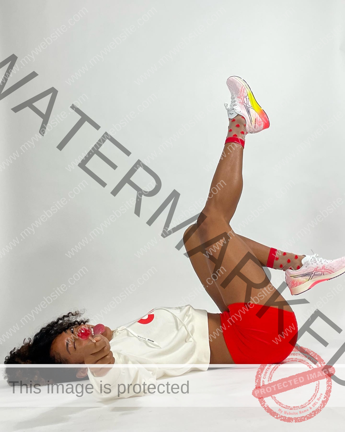 kristina-knott-philippines-knottyourcheese-x-18304 Kristina Knott, track and field star from Philippines, lies on a white background in sporty attire, smiling with a red lollipop.