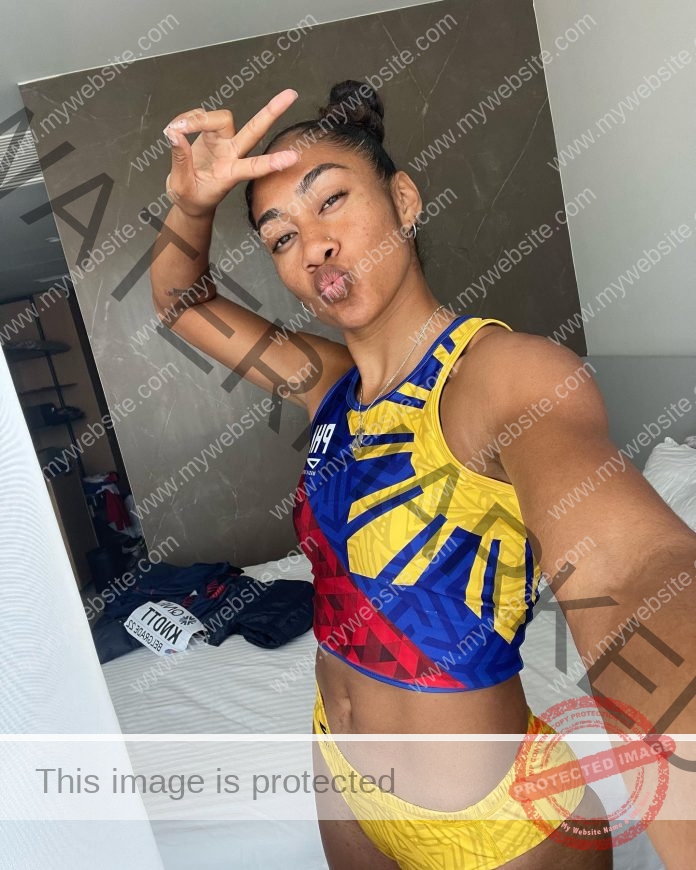 Kristina Knott, track and field star from Philippines, makes a peace sign and puckers her lips for a selfie in a colorful athletic outfit.