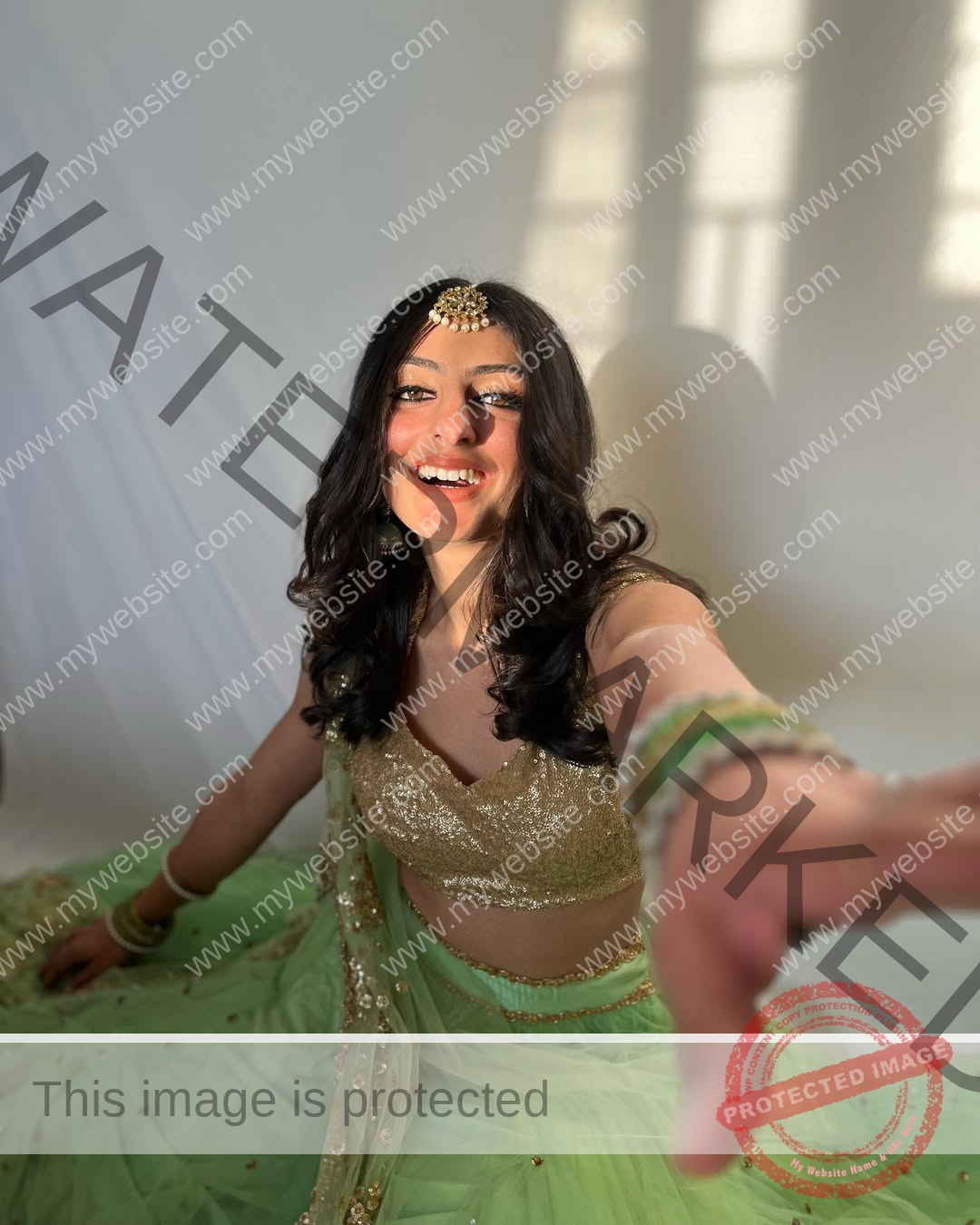 niharika-vashisht-india-niharika.vashhisht-05585 Niharika Vashisht, track and field star from India, in a gold blouse and green lehenga sits smiling on the floor, reaching forward.