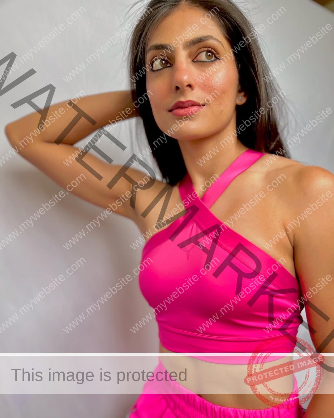 niharika-vashisht-india-niharika.vashhisht-05612 Niharika Vashisht, track and field star from India, stands in a pink crop top and shorts, gazing upward with arm behind her head.