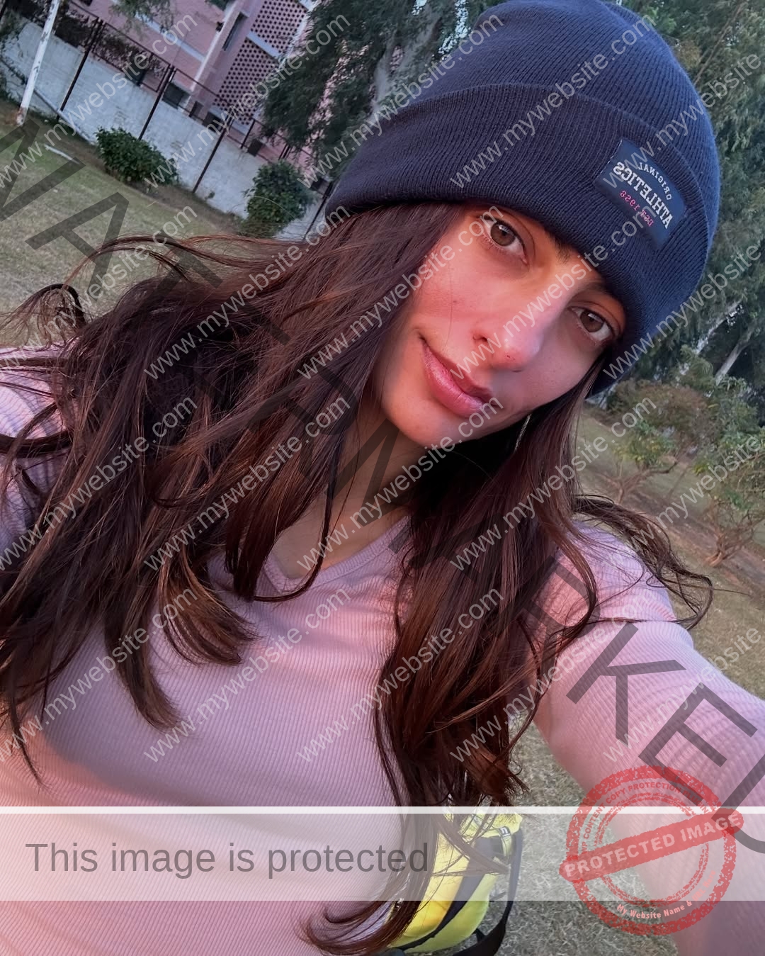 niharika-vashisht-india-niharika.vashhisht-05974 Niharika Vashisht, track and field star from India, with long brown hair in a dark beanie and pink top, takes a selfie outdoors.