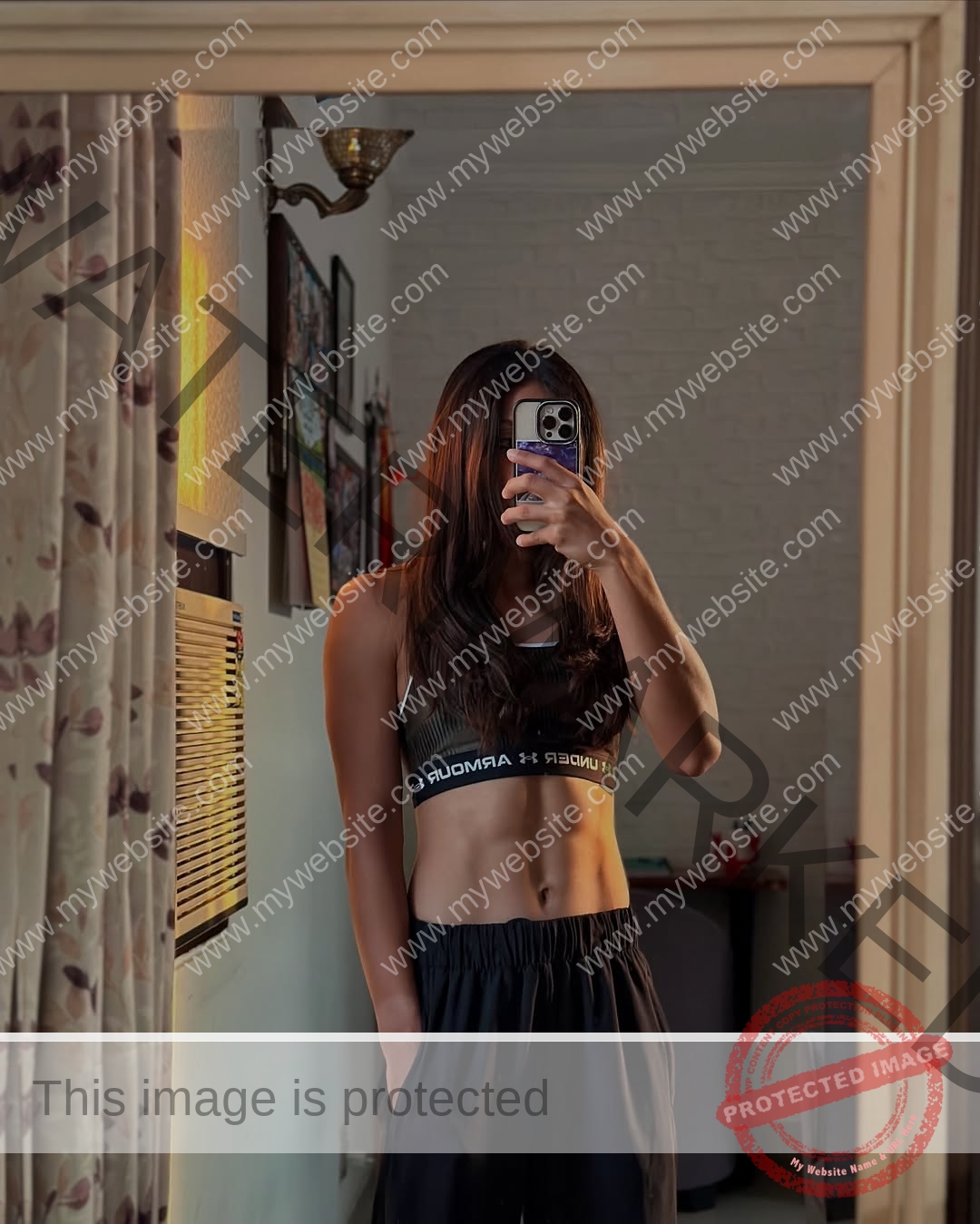 niharika-vashisht-india-niharika.vashhisht-06071 Niharika Vashisht, track and field star from India, in a sports bra and black pants takes a mirror selfie indoors, phone covering her face.