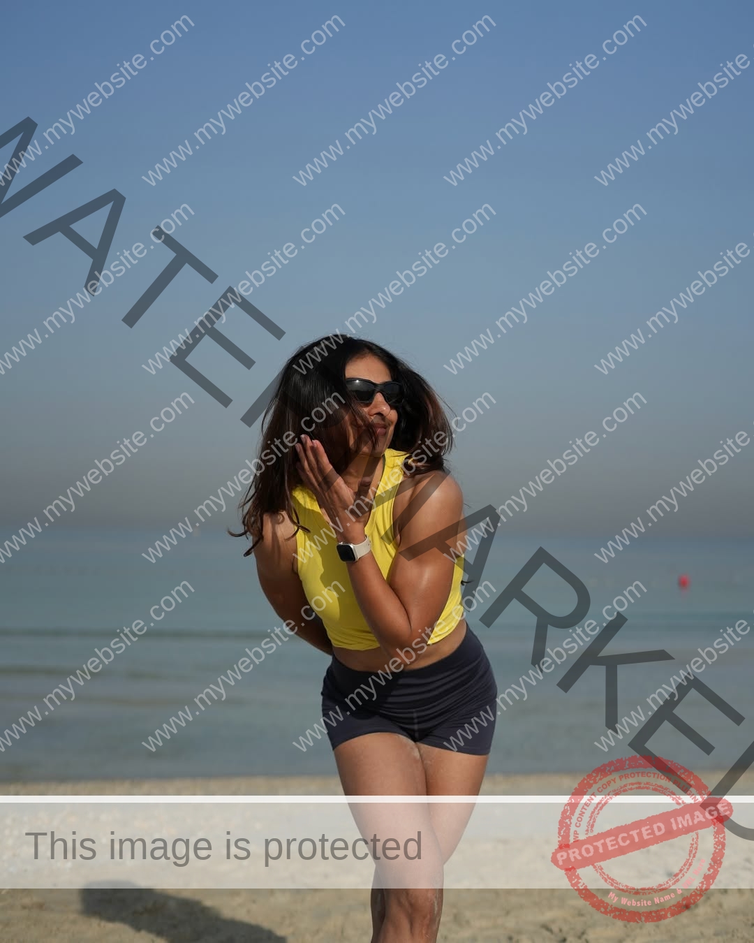 niharika-vashisht-india-niharika.vashhisht-06115 Niharika Vashisht, track and field star from India, wears a yellow tank top and poses playfully on a beach under clear blue sky.
