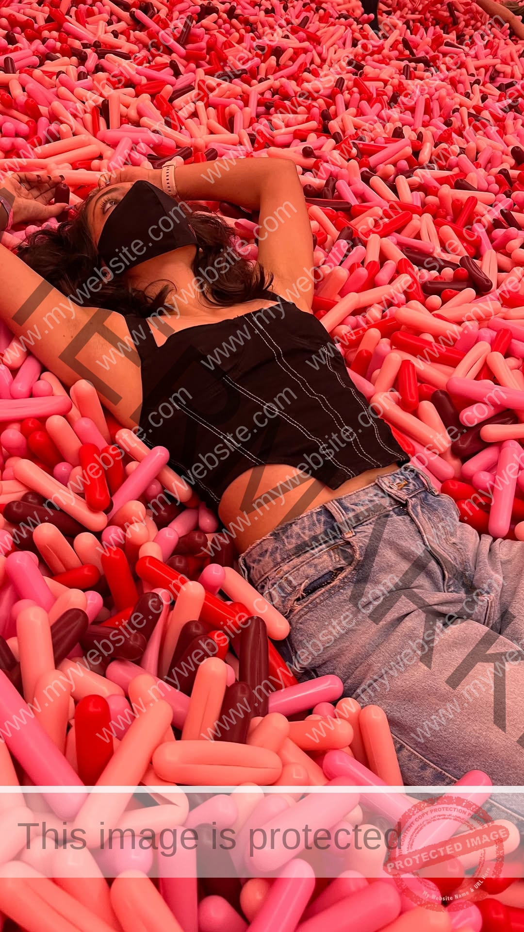 niharika-vashisht-india-niharika.vashhisht-06152 Niharika Vashisht, track and field star from India, in mask, black top, blue jeans, lies on pink and red foam cylinders, arms above head.