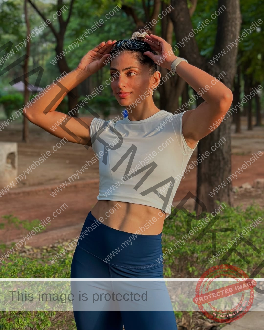 niharika-vashisht-india-niharika.vashhisht-06168 Niharika Vashisht, track and field star from India, stands outdoors in a white crop top and navy leggings, adjusting sunglasses.