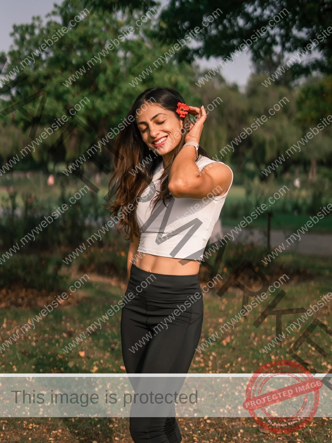niharika-vashisht-india-niharika.vashhisht-06213 Niharika Vashisht, track and field star from India, smiles outdoors with a red flower near her ear, eyes closed, in sporty attire.