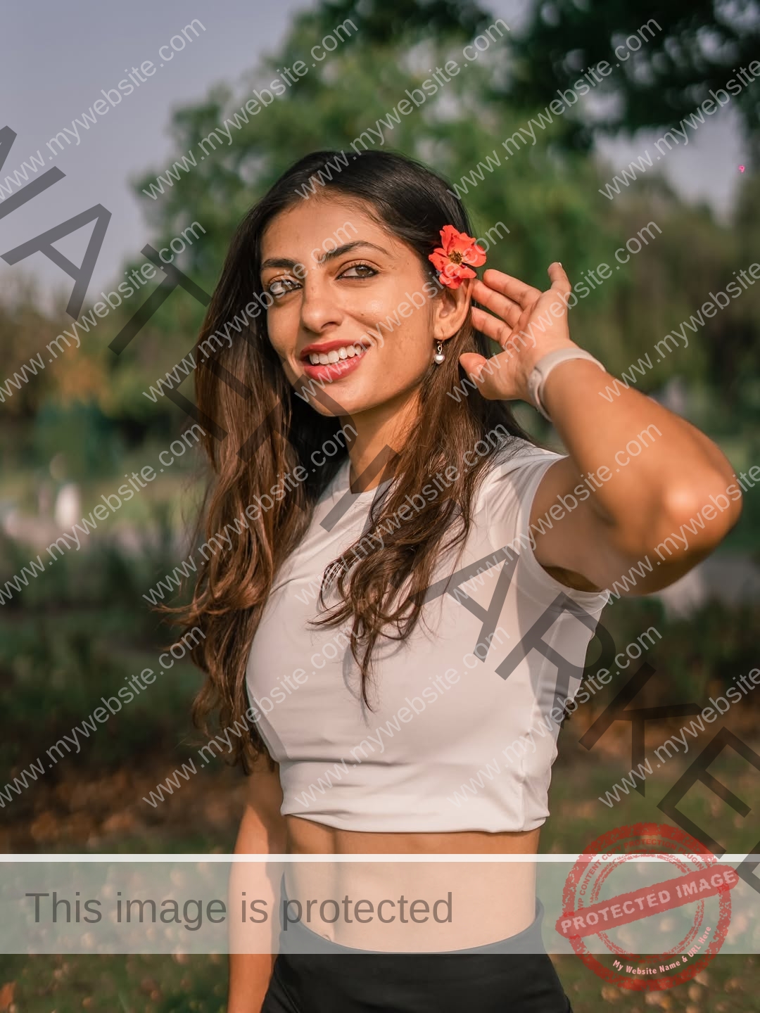 niharika-vashisht-india-niharika.vashhisht-06214 Niharika Vashisht, track and field star from India, with long brown hair in a white crop top, stands smiling in a sunny green park.