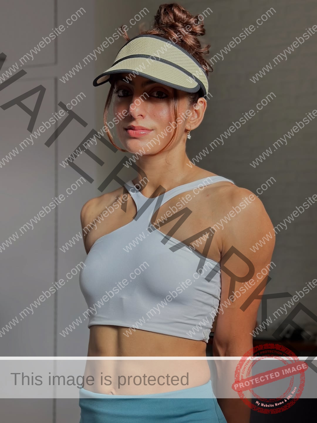 niharika-vashisht-india-niharika.vashhisht-06218 Niharika Vashisht, track and field star from India, in a gray sports bra, blue leggings, beige visor, smiling indoors softly lit.
