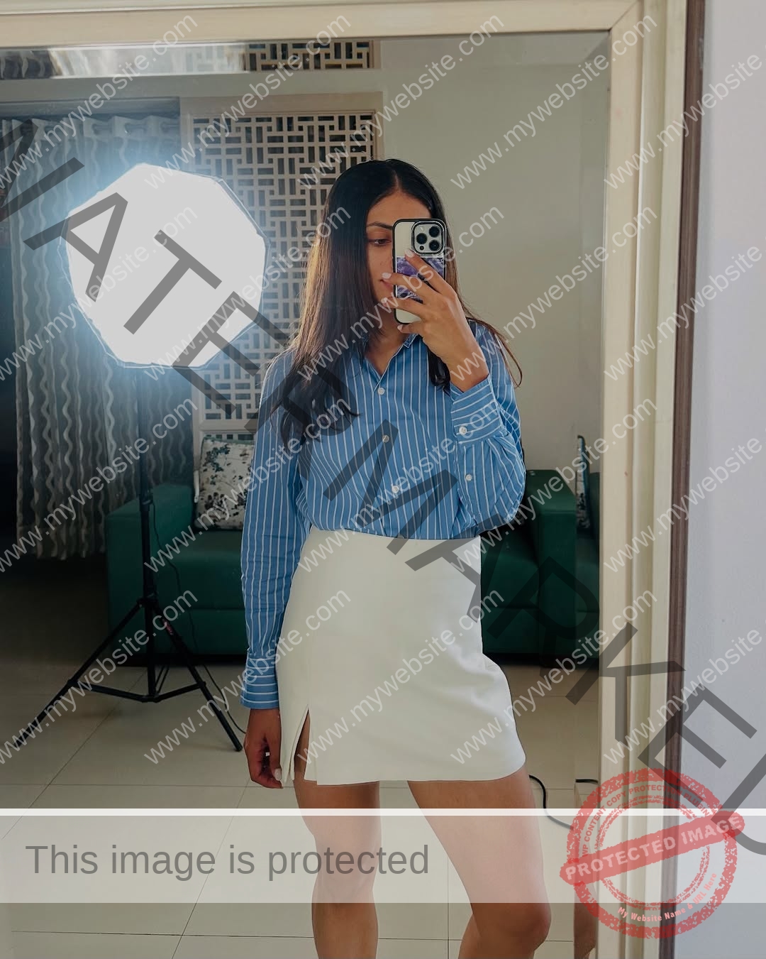niharika-vashisht-india-niharika.vashhisht-06227 Niharika Vashisht, track and field star from India, takes a mirror selfie in blue striped shirt and white slit skirt; studio light, green sofa behind.
