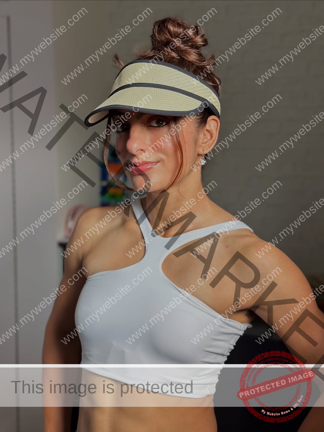 niharika-vashisht-india-niharika.vashhisht-06236 Niharika Vashisht, track and field star from India, wears a beige visor, white asymmetrical crop top, and smiles indoors with hair in a bun.