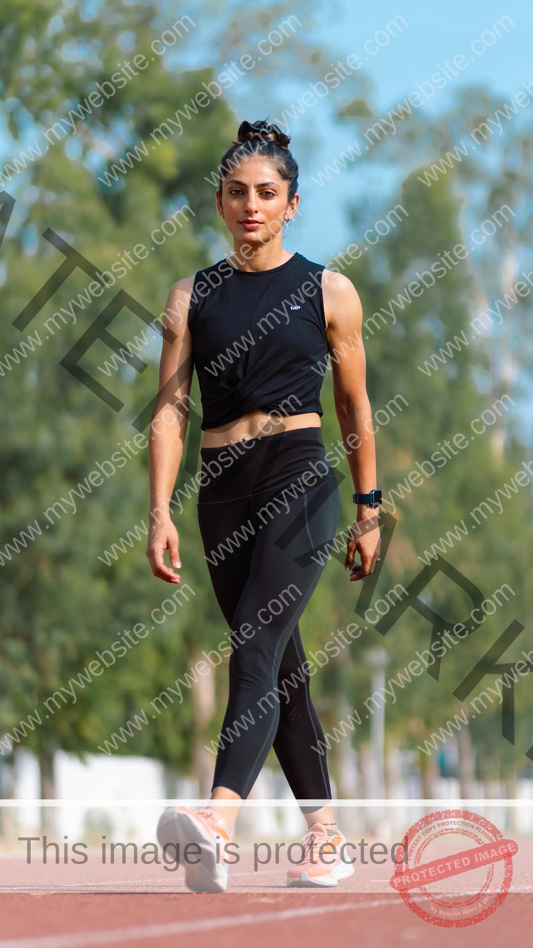 niharika-vashisht-india-niharika.vashhisht-06249 Niharika Vashisht, track and field star from India, walks on an outdoor track in black athletic wear and orange running shoes.