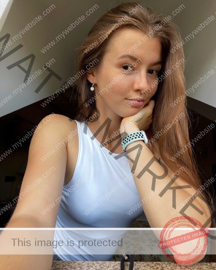Oleksandra Nesterenko, track and field star from Ukraine, with long brown hair, white top and smartwatch, smiles at a table.