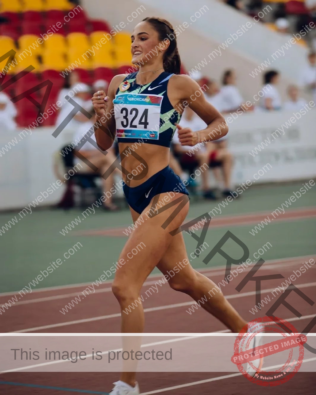 polina-tkalich-russia-p_a_tkalich-10820 Polina Tkalich, track and field star from Russia, in blue running outfit with bib 324 runs on a track in a stadium with spectators.