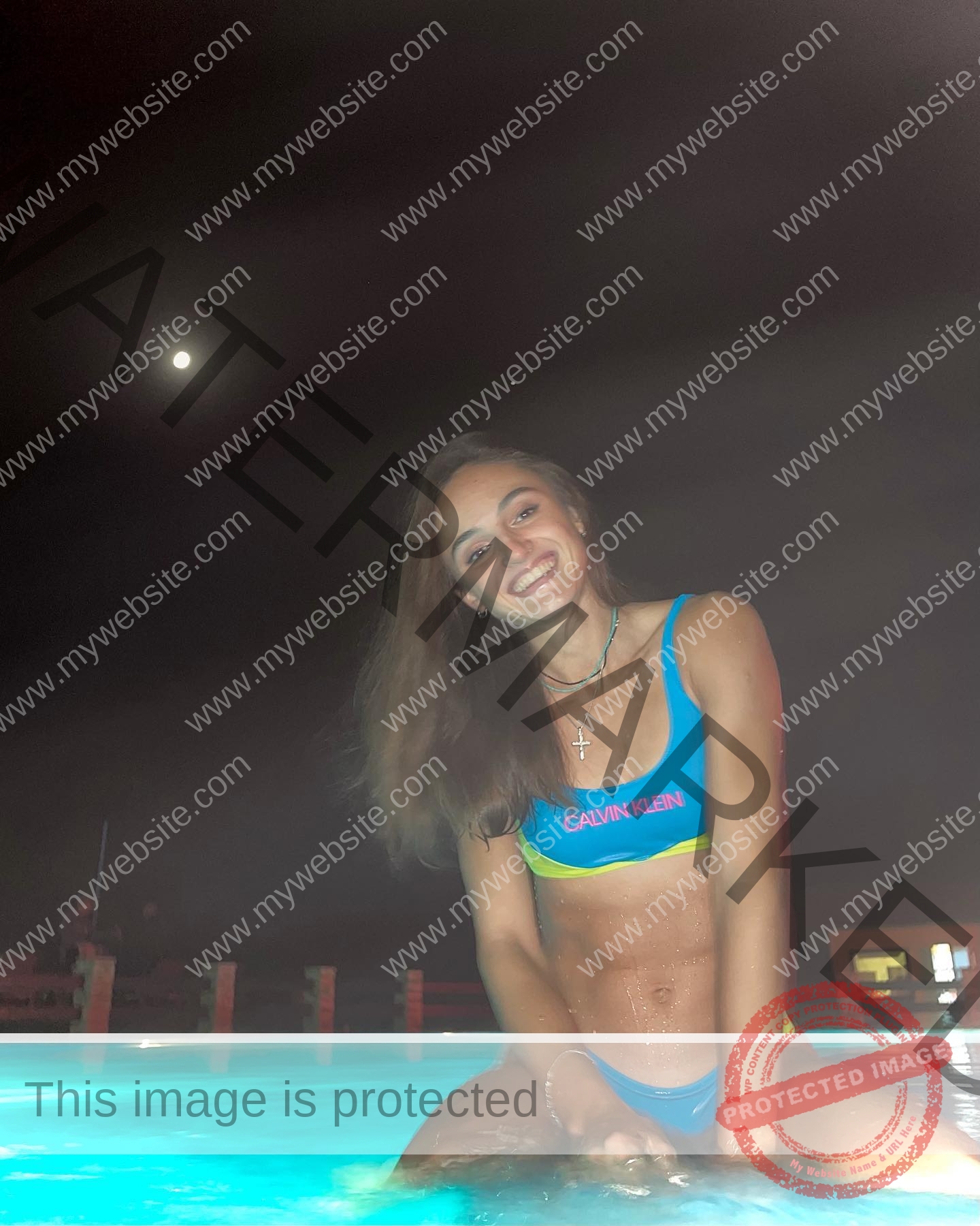 polina-tkalich-russia-p_a_tkalich-10871 Polina Tkalich, track and field star from Russia, smiles in a blue and yellow Calvin Klein bikini in a lit pool at night under the moon.