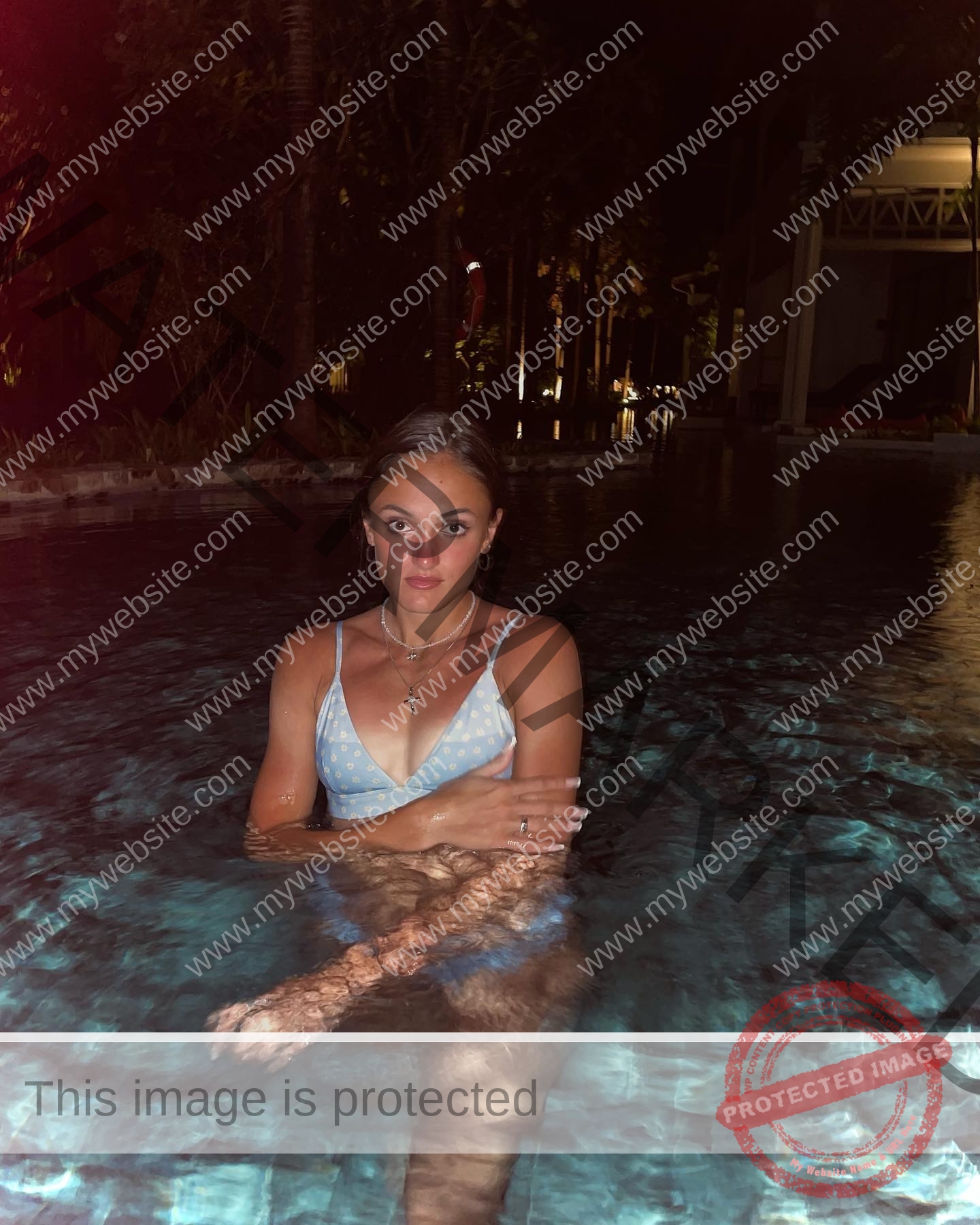 polina-tkalich-russia-p_a_tkalich-10992 Polina Tkalich, track and field star from Russia stands in a pool at night in a blue bikini top, arms crossed, looking at camera.