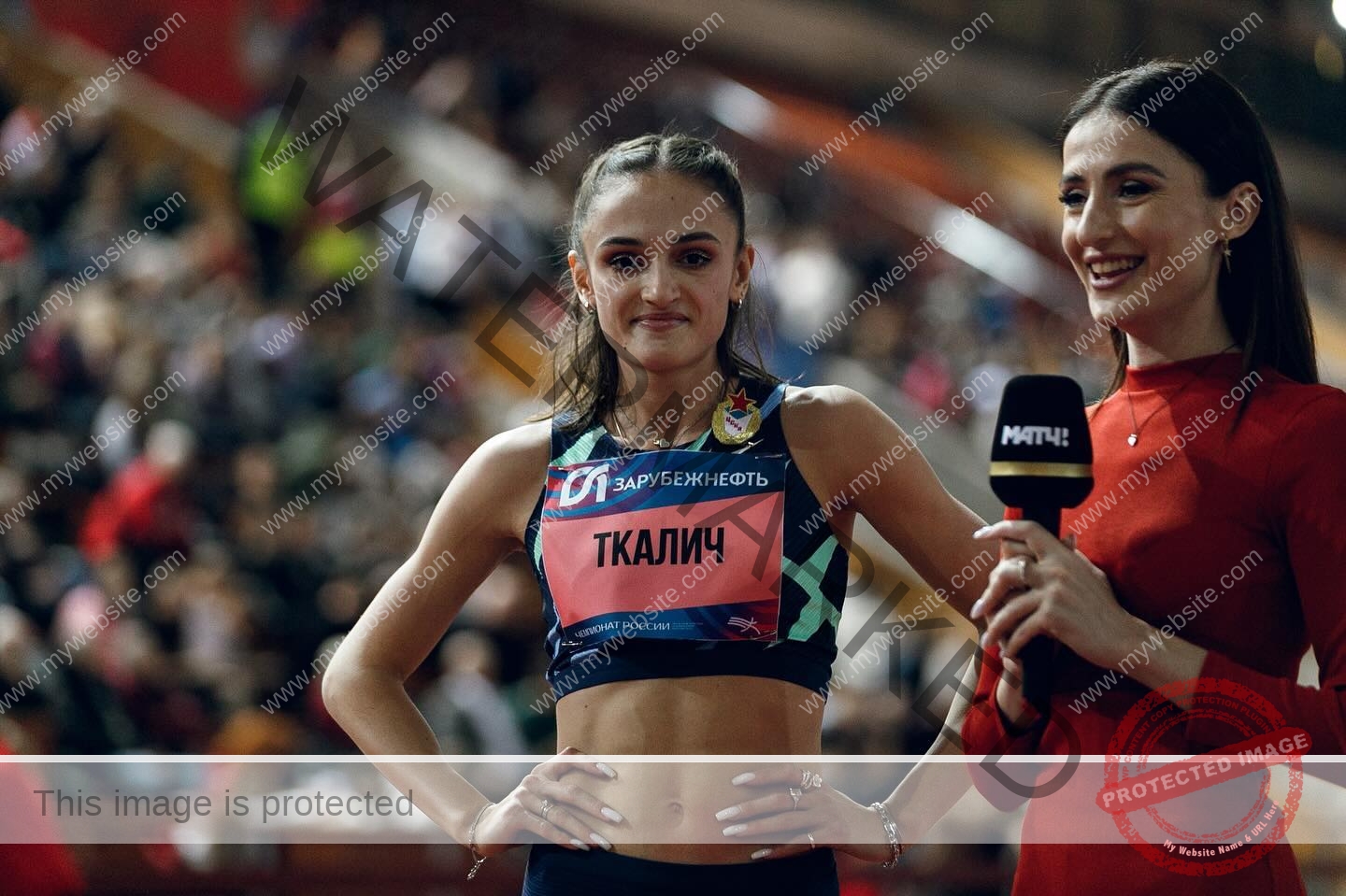 polina-tkalich-russia-p_a_tkalich-11093 Polina Tkalich, track and field star from Russia, stands smiling with hands on hips as she’s interviewed by a woman in a red dress.