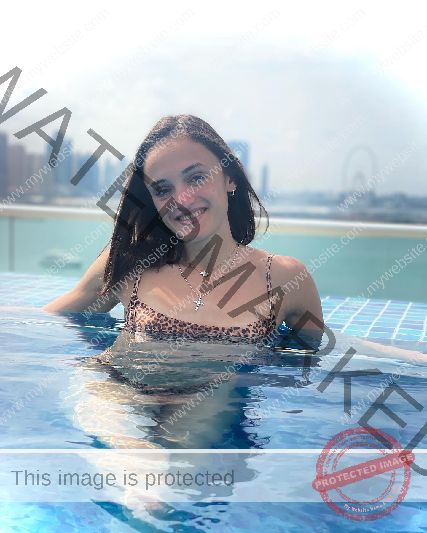 polina-tkalich-russia-p_a_tkalich-11103 Polina Tkalich, track and field star from Russia, smiles in a rooftop pool wearing leopard print swimsuit; skyline and Ferris wheel behind.