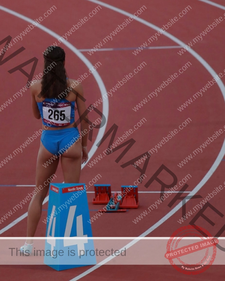 polina-tkalich-russia-p_a_tkalich-11266 Polina Tkalich, track and field star from Russia, in blue uniform #265 stands in lane 4 on red track, prepping at starting blocks.