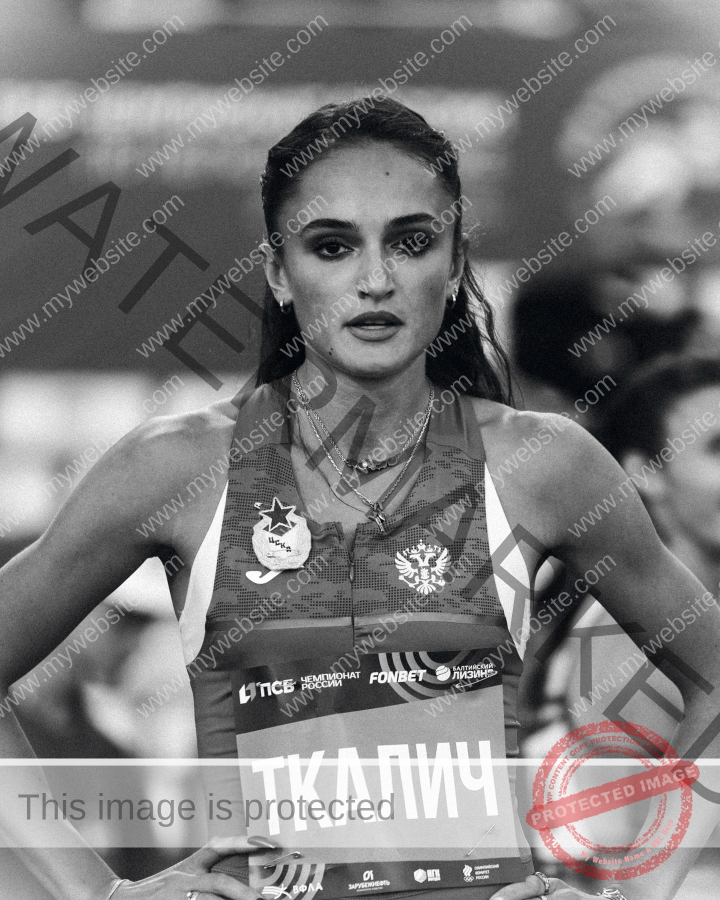 polina-tkalich-russia-p_a_tkalich-11275 Polina Tkalich, track and field star from Russia, stands hands on hips in black and white, race bib reads ТКАЛИЧ.
