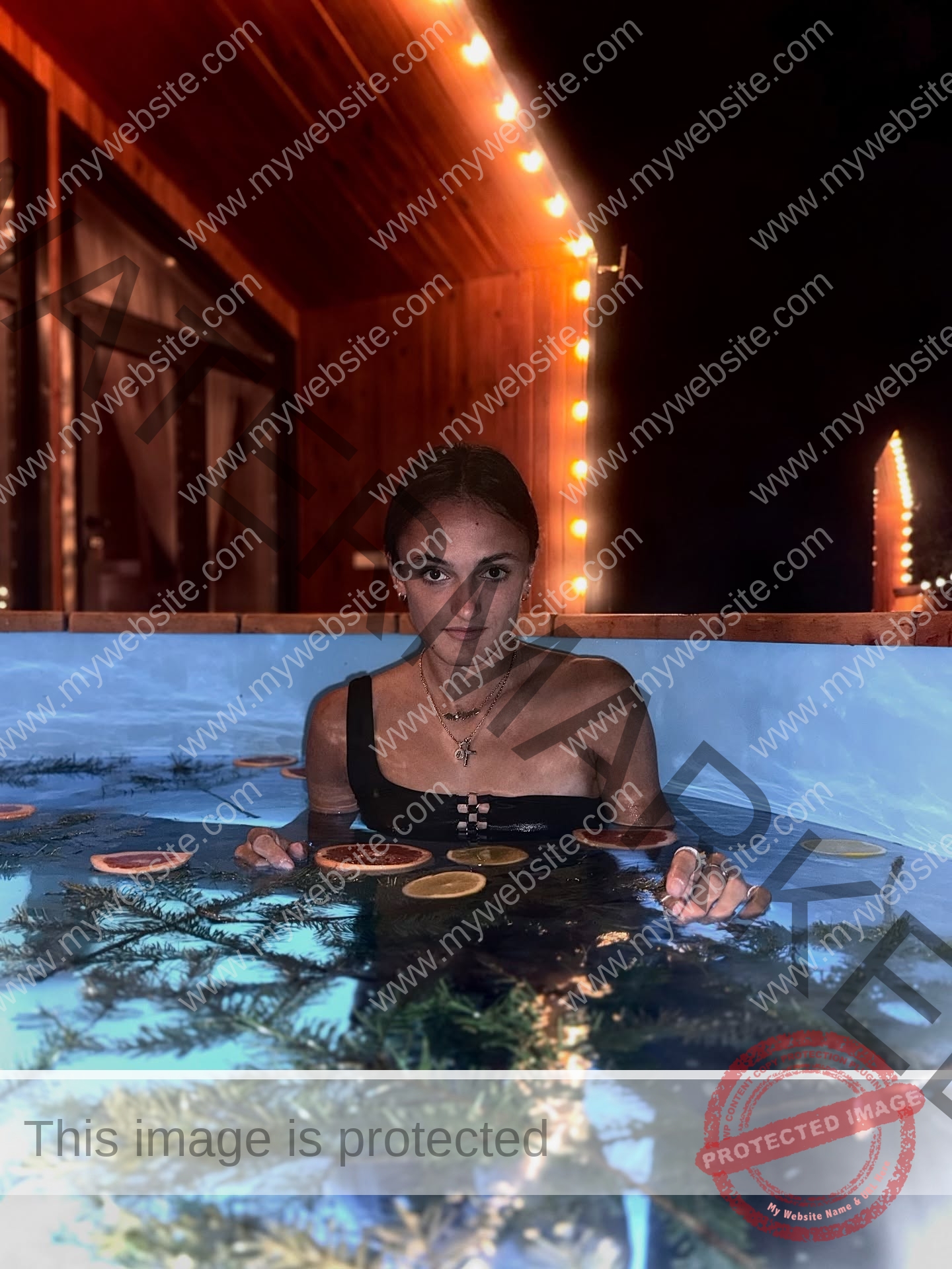 polina-tkalich-russia-p_a_tkalich-11339 Polina Tkalich, track and field star from Russia, sits in a black swimsuit in an outdoor hot tub at night among citrus slices and lights.