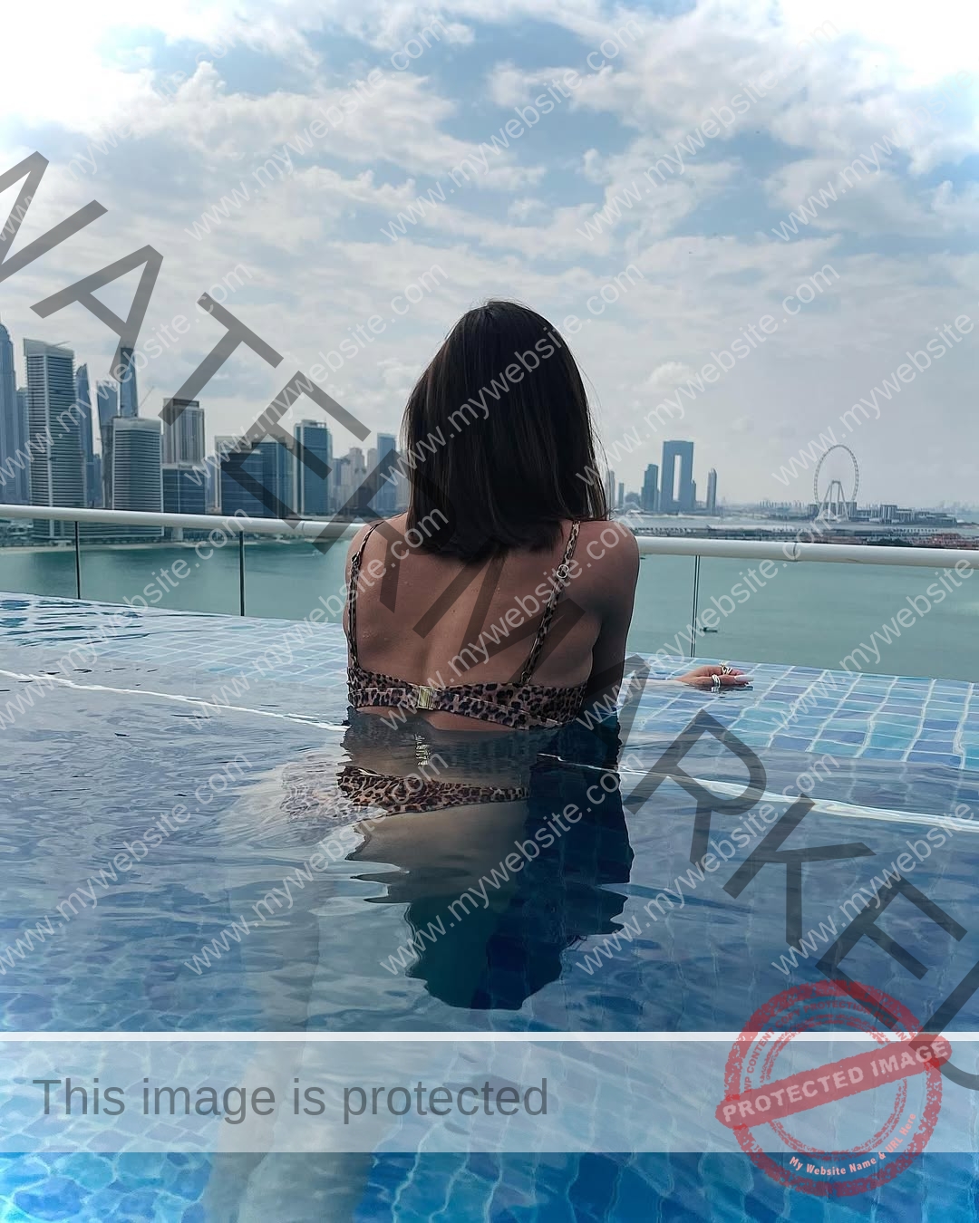 polina-tkalich-russia-p_a_tkalich-12062 Polina Tkalich, track and field star from Russia, in a leopard print bikini sits at an infinity pool edge facing a city skyline.