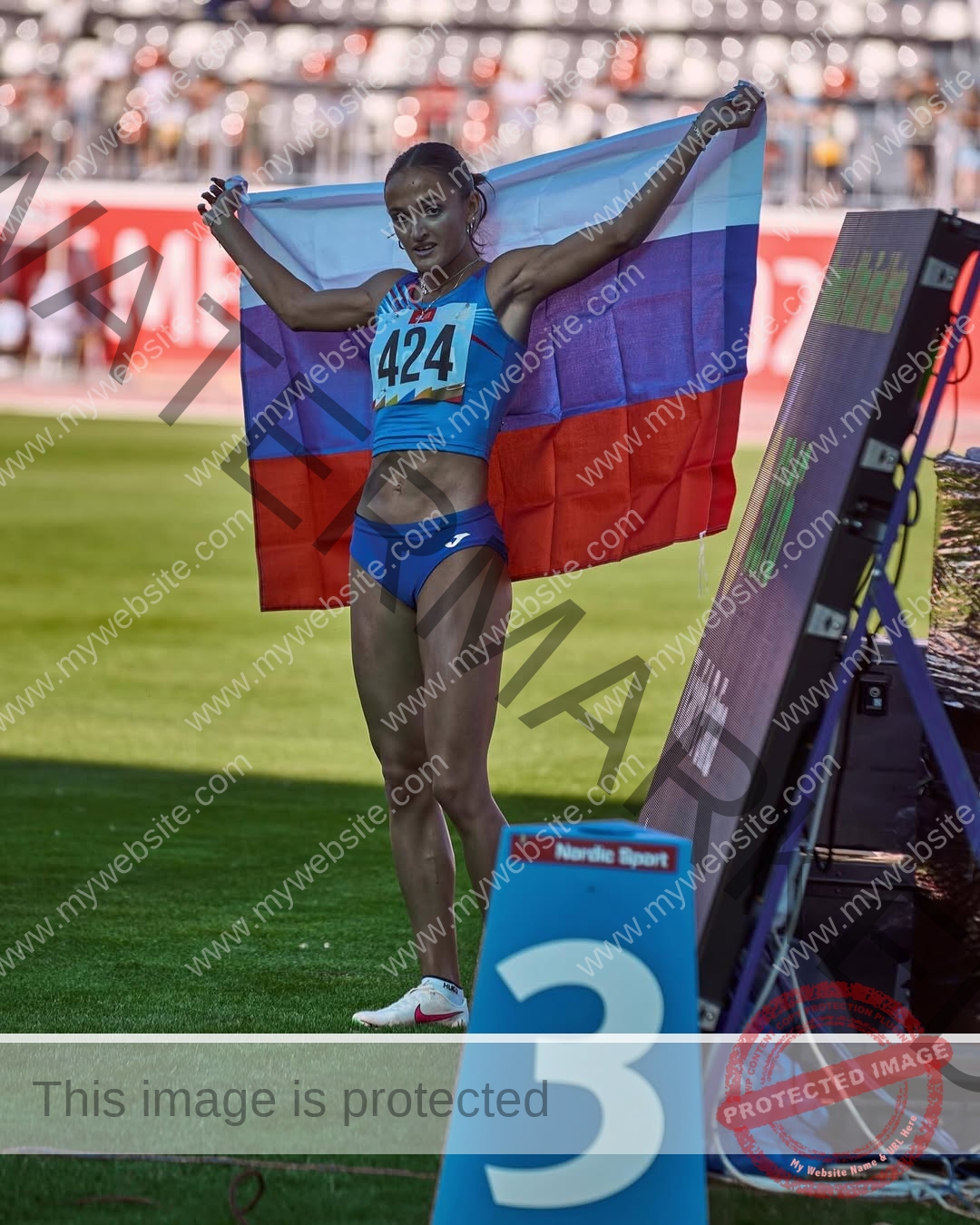 polina-tkalich-russia-p_a_tkalich-12101 Polina Tkalich, track and field star from Russia, in blue sportswear holds the Russian flag near a 3rd-place sign on grass.