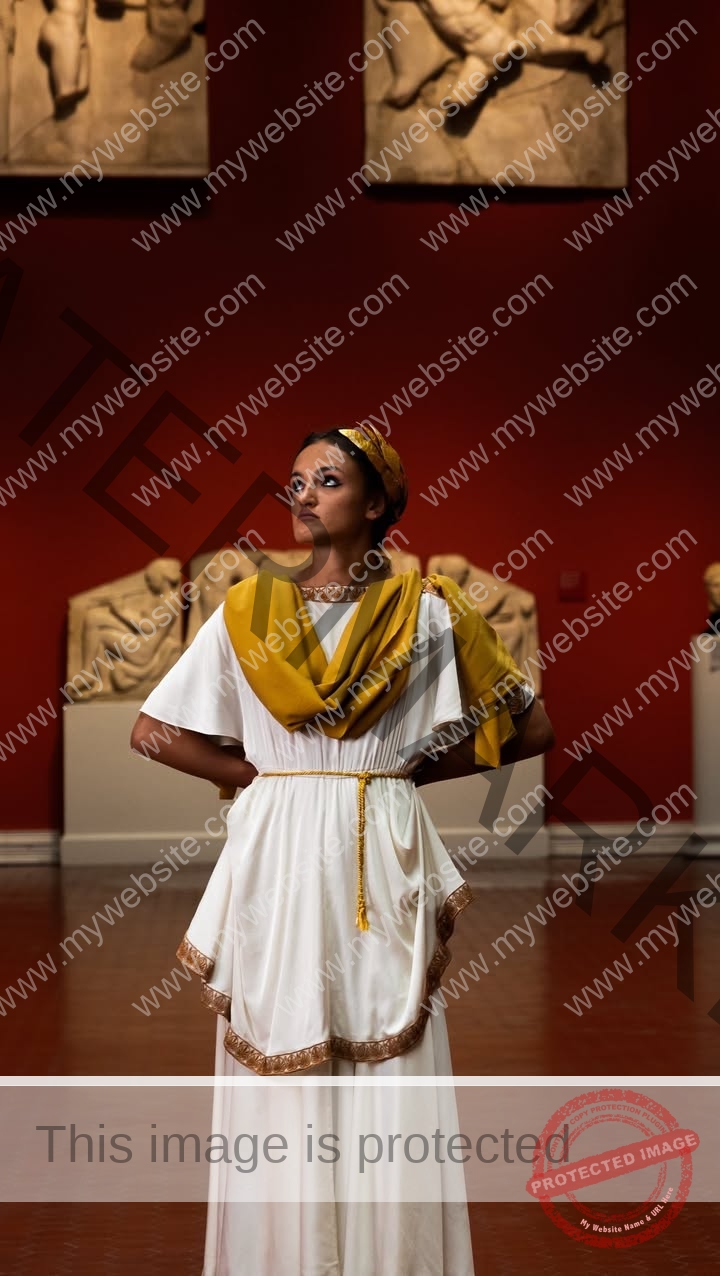 polina-tkalich-russia-p_a_tkalich-12238 Polina Tkalich, track and field star from Russia, in a white Greco-Roman dress stands hands on hips amid statues and red walls.