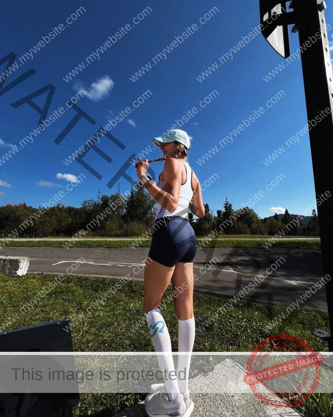 rufina-kotik-ukraine-rufina.kotik14-u18-01906 Rufina Kotik, track and field star from Ukraine, stands on grass in athletic wear, holding a jump rope behind her shoulders.