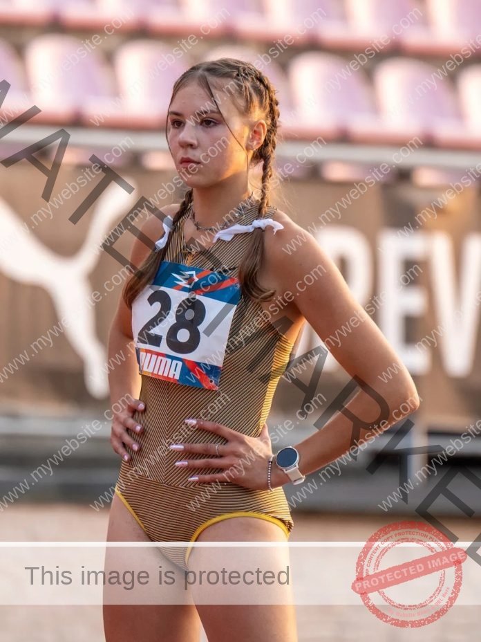 Rufina Kotik, track and field star from Ukraine, stands with hands on hips in a stadium, striped leotard and bib 28 visible.