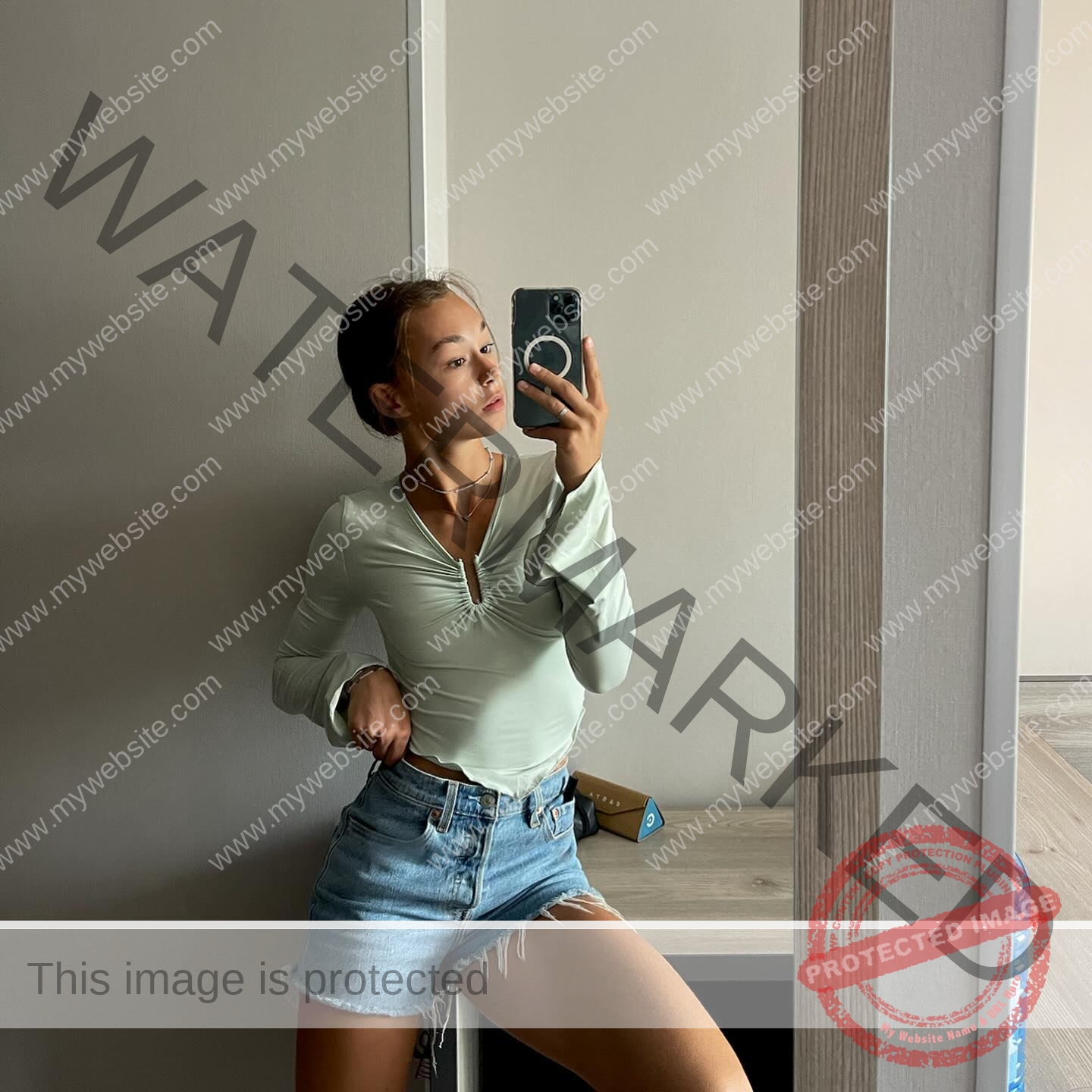 sasha-liubanska-ukraine-sasha_liubanska-u20-x-06038 Sasha Liubanska, track and field star from Ukraine, wears a light green long-sleeve top and denim shorts posing for a mirror selfie.