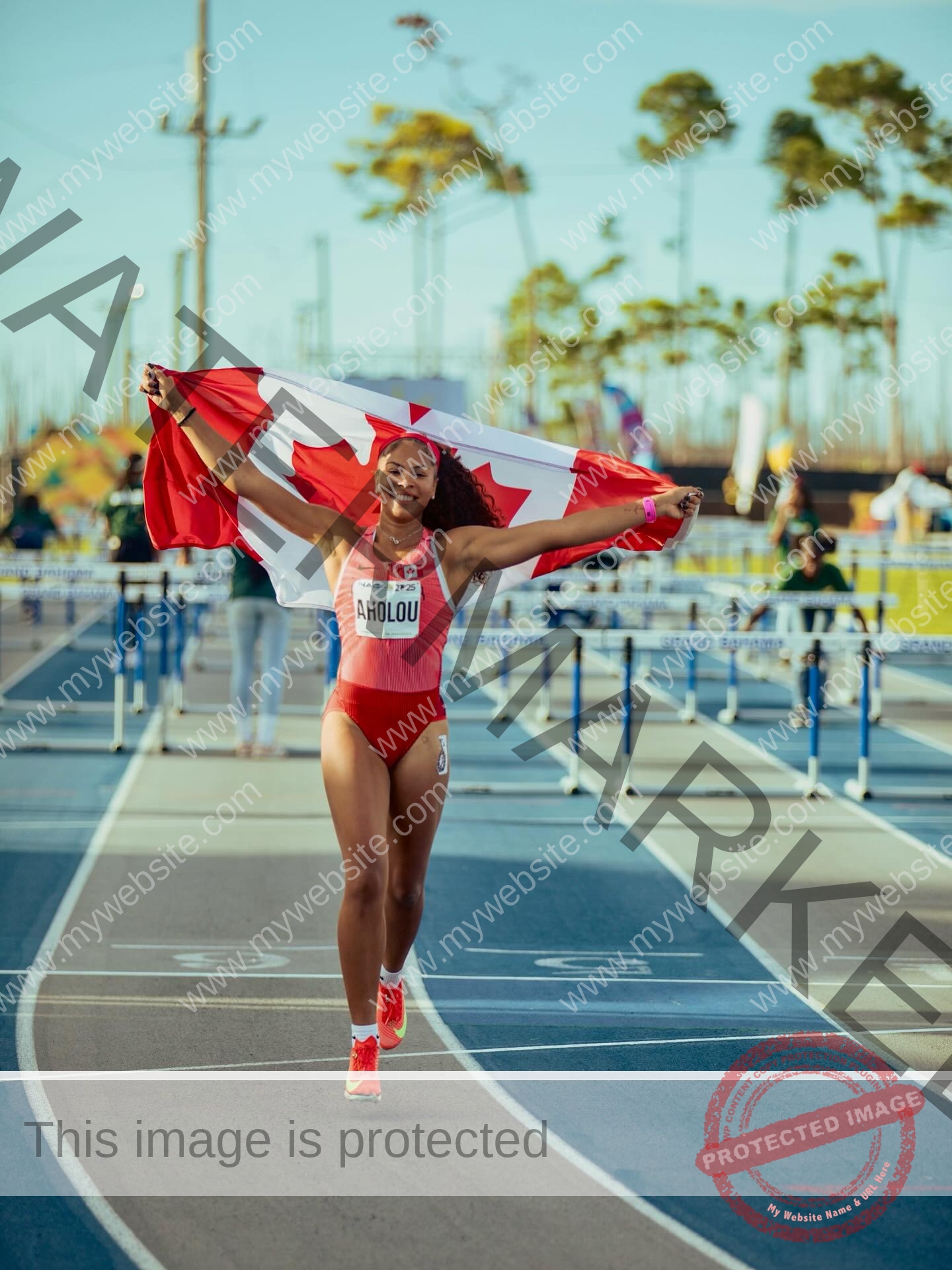 tatiana-aholou-canada-tatianaaholou-00502 Tatiana Ahoulou, track and field star from Canada, smiles holding a Canadian flag above her head on a track after a race.