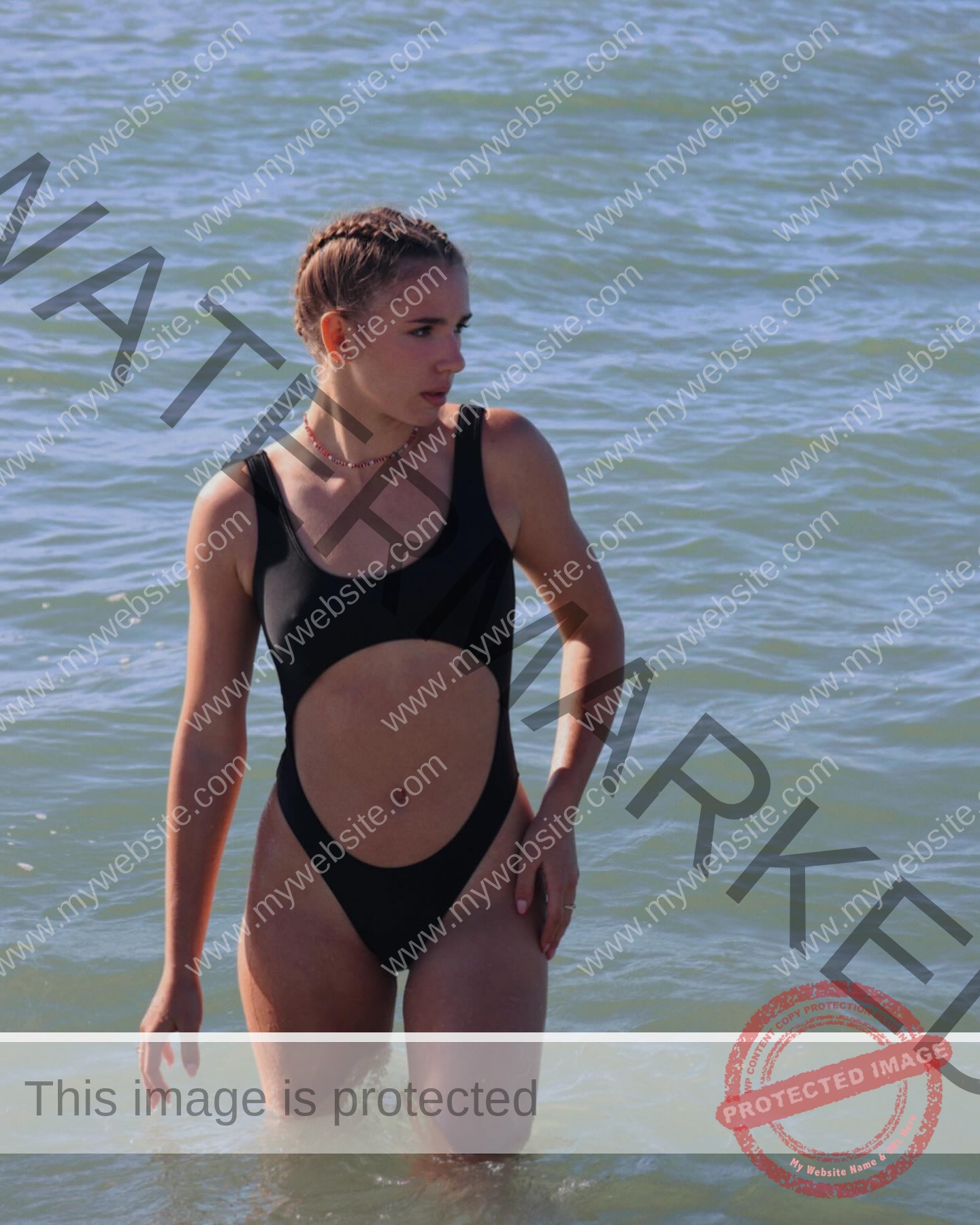 viktoriya-antipova-russia-viichkaaaaa-03611 Viktoriya Antipova, track and field star from Russia stands in sunlit ocean water wearing a black cut-out swimsuit, hair in braids.