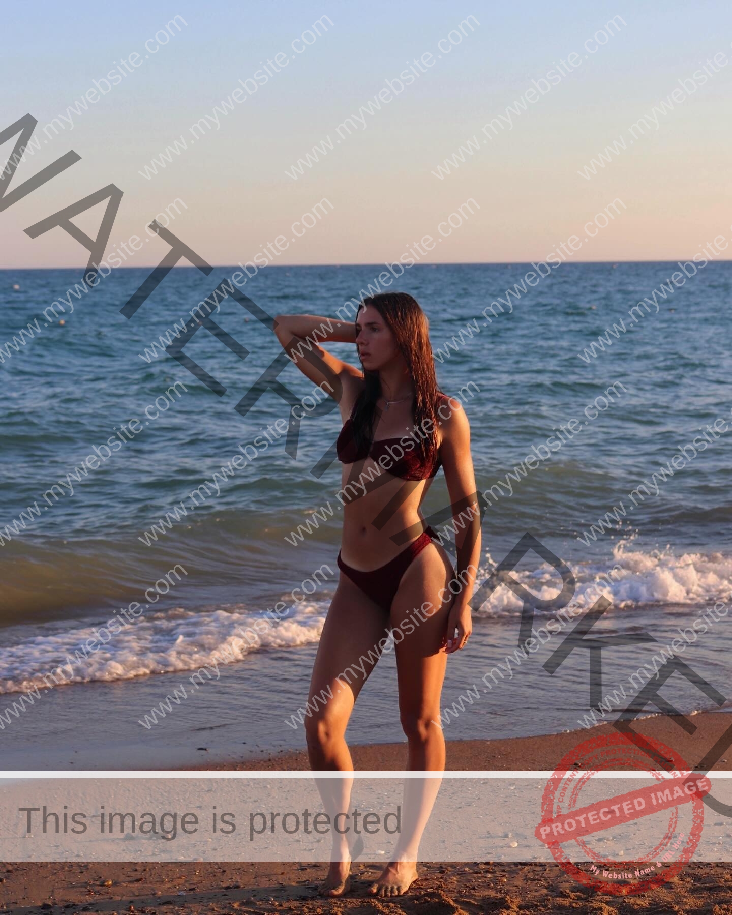 viktoriya-antipova-russia-viichkaaaaa-03660 Viktoriya Antapova, track and field star from Russia, stands on a sandy beach at sunset in a maroon bikini, gazing into the distance.