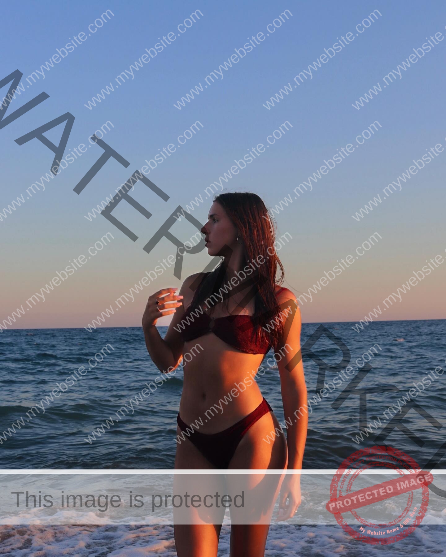 viktoriya-antipova-russia-viichkaaaaa-03663 Viktoriya Antipova, track and field star from Russia, stands in a burgundy bikini on the shore at sunset, gazing to the side.