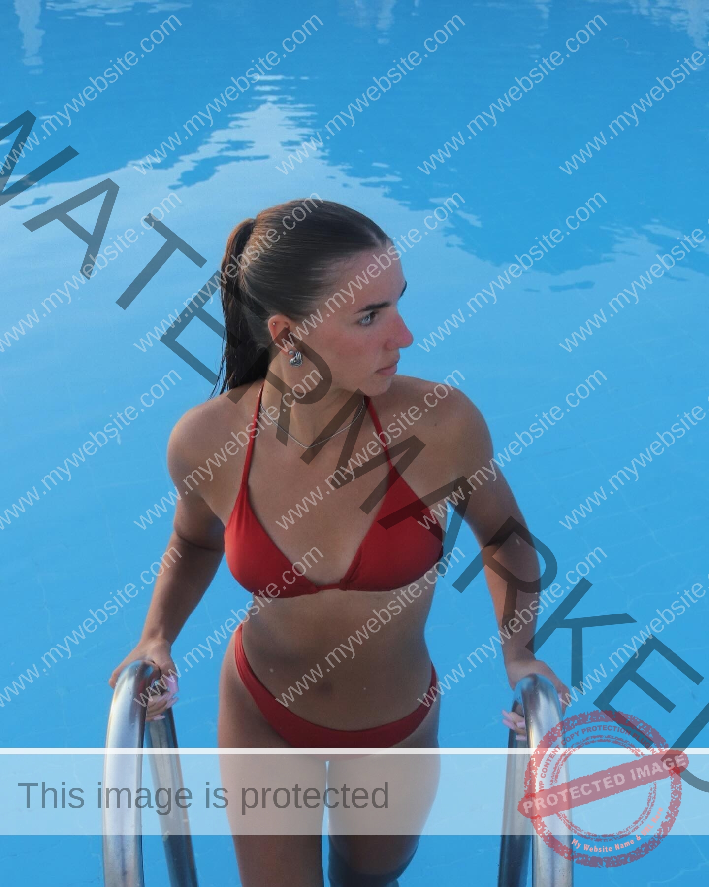 viktoriya-antipova-russia-viichkaaaaa-03673 Viktoriya Antipova, track and field star from Russia, in a red bikini climbs a pool ladder out of clear water, looking right.